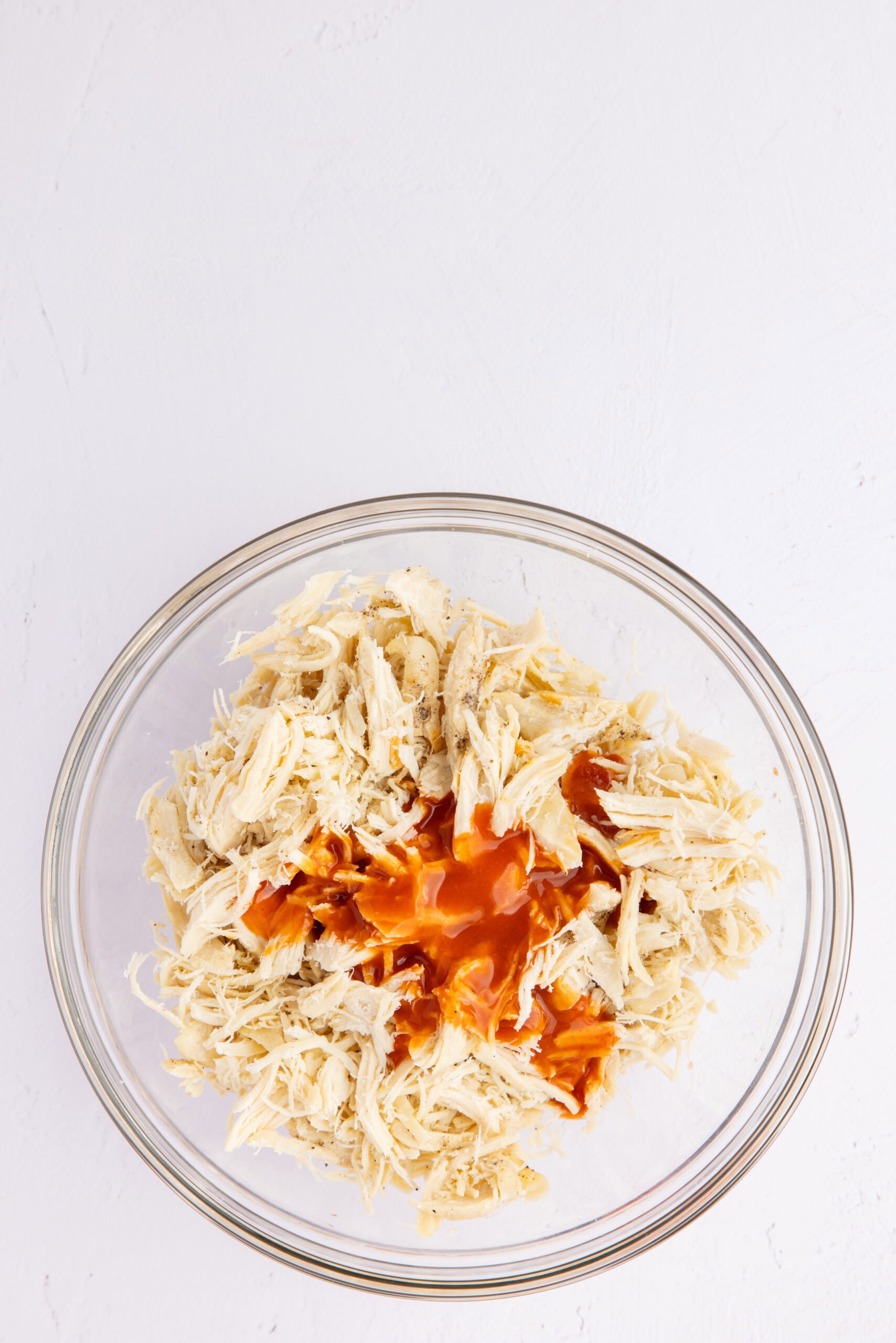 Shredded chicken with hot sauce in a mixing bowl