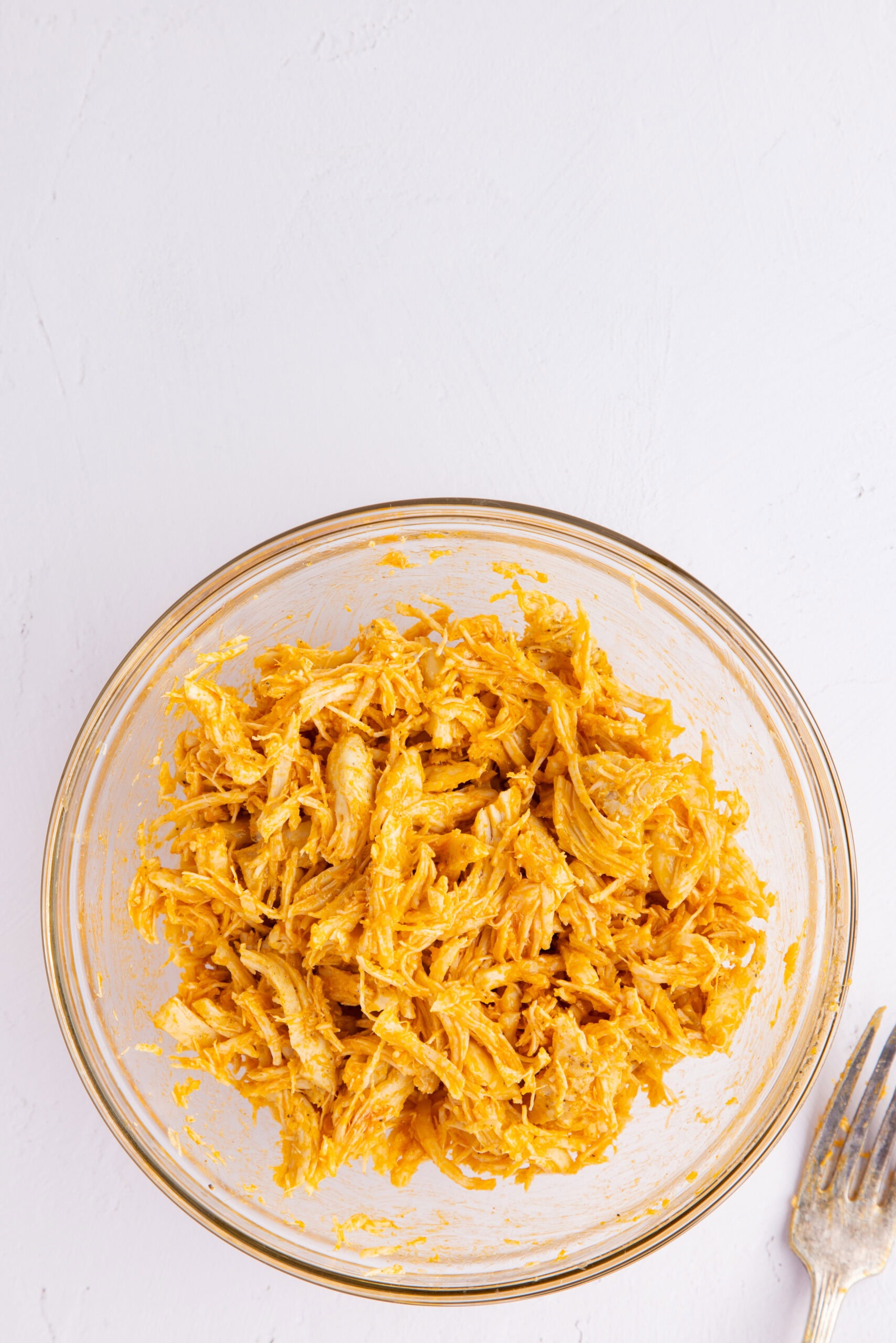 Buffalo chicken shredded in a mixing bowl, ready to be topped on a baking potato
