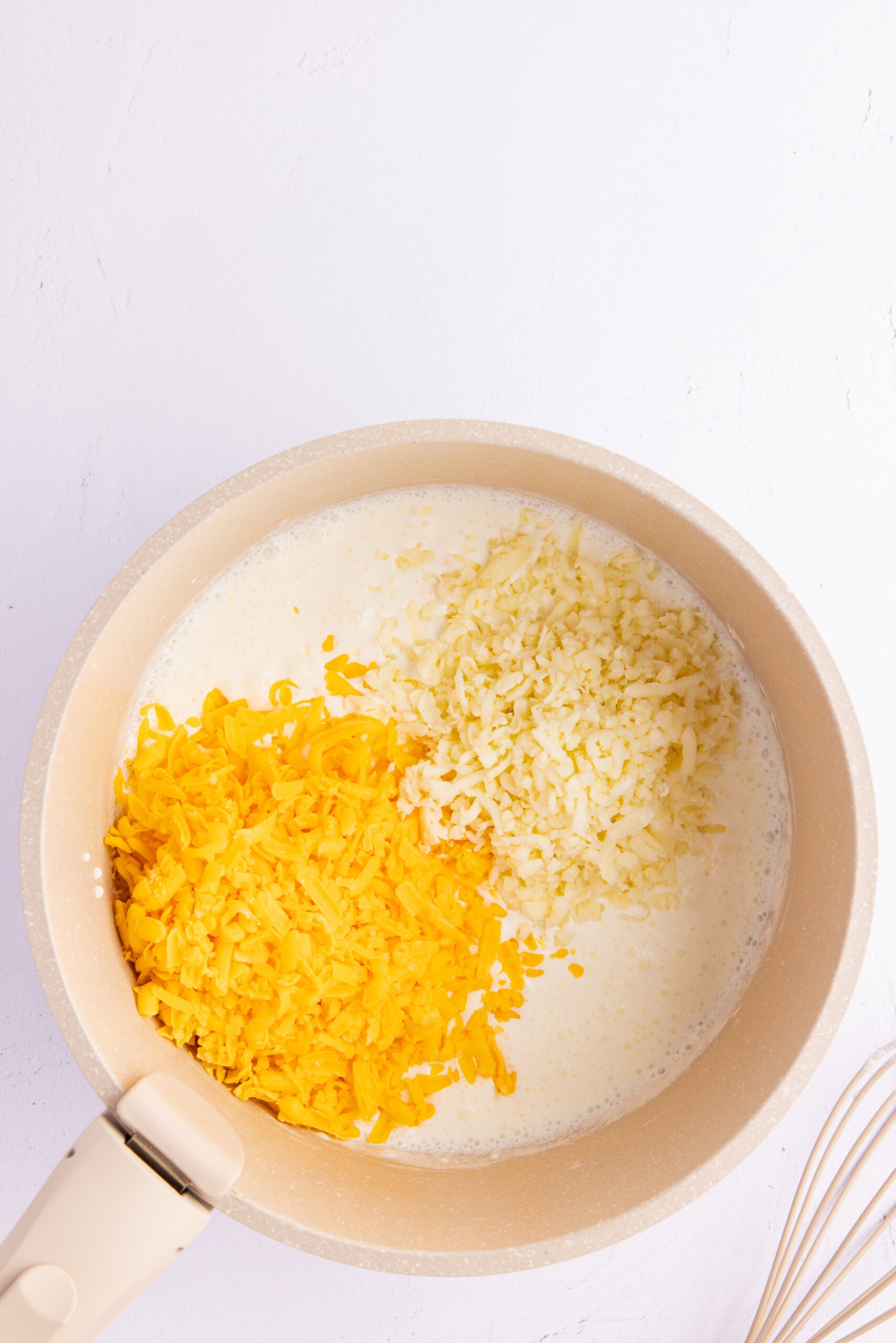 Ingredients in sauce pan to be whisked to make the cheese sauce: cornstarch, heavy cream, cheddar and mozarella cheese