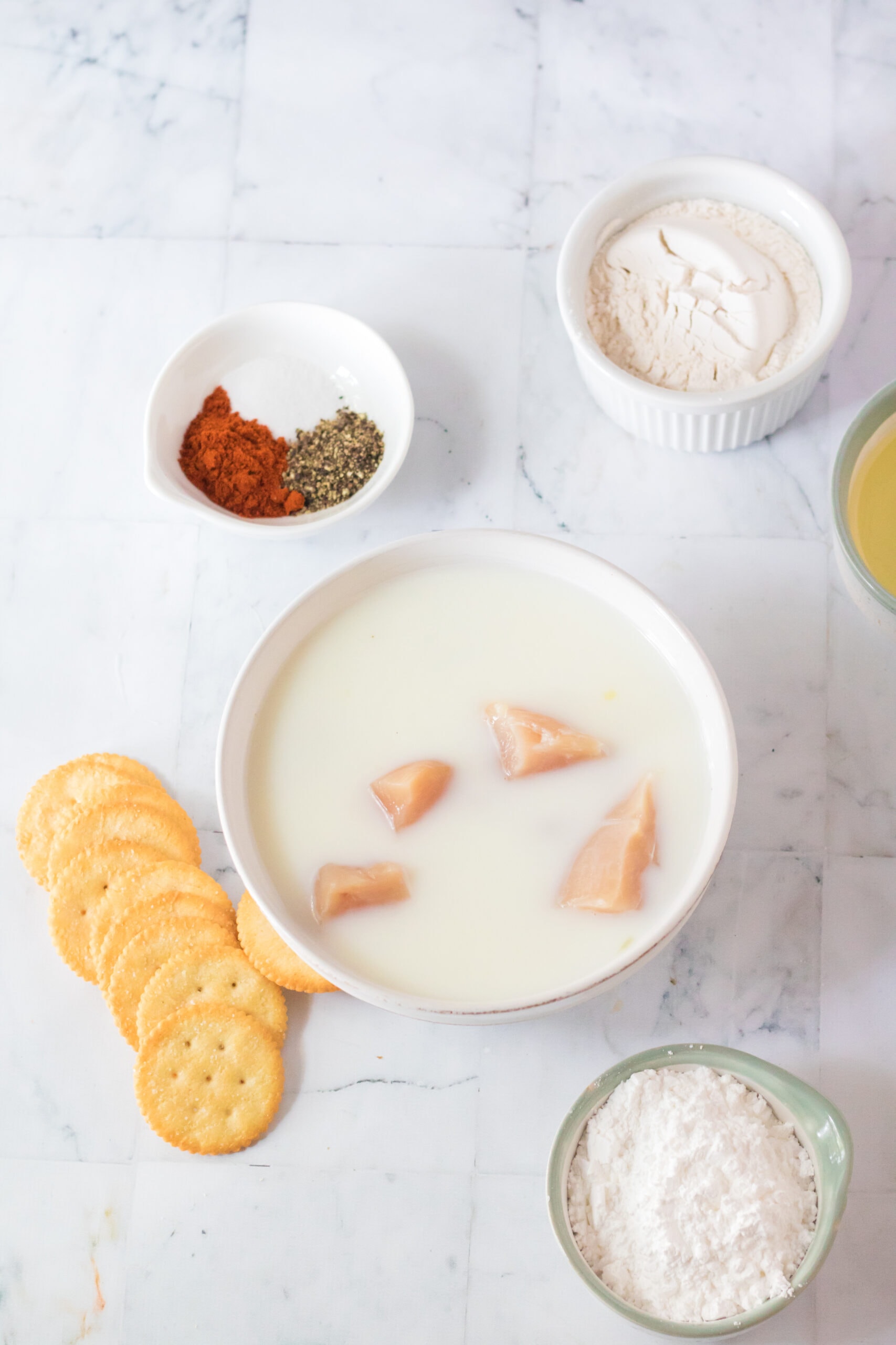 Chicken that has been diced into nugget sized, placed in a bowl with milk and pickle juice to marinate