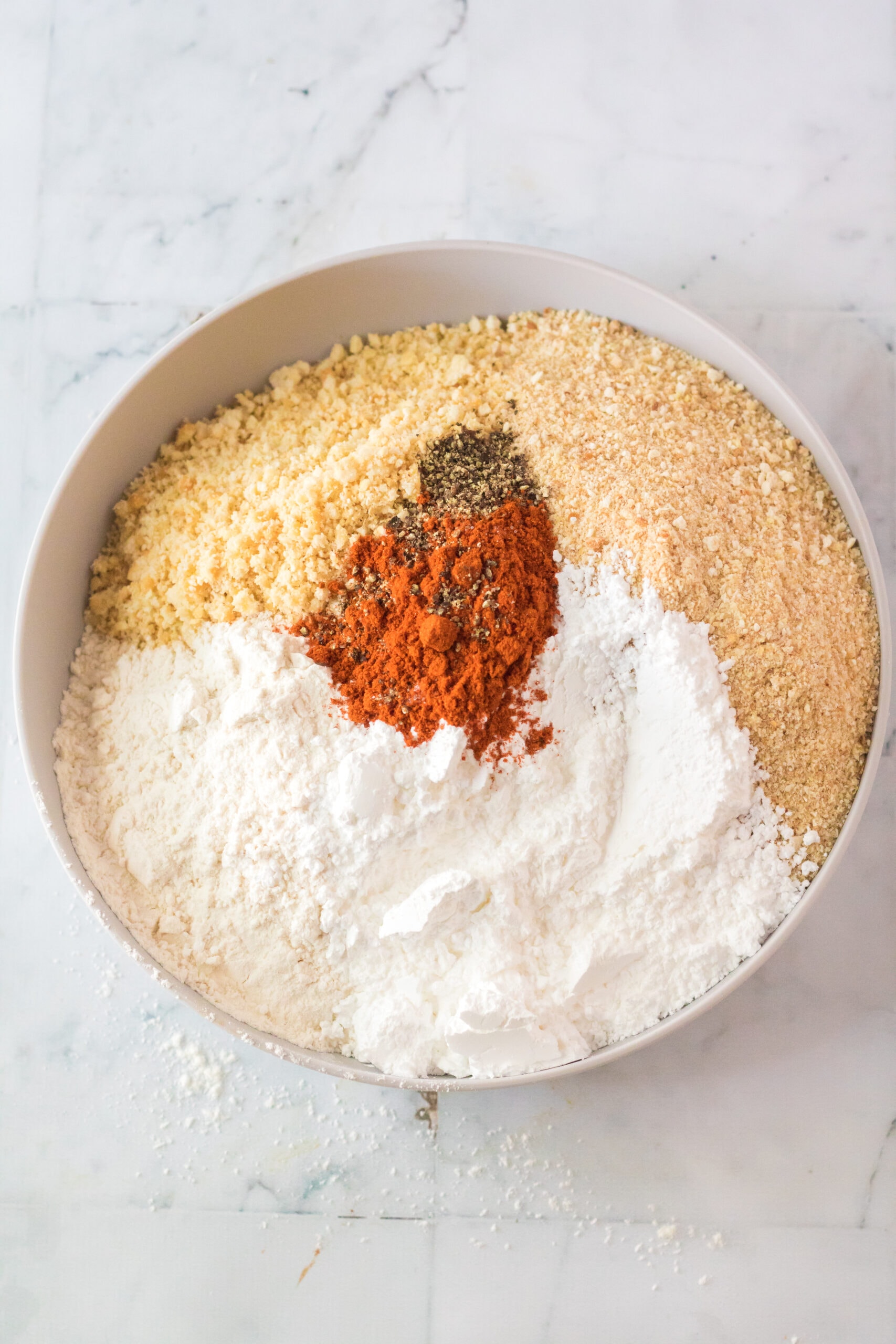 Cracker crumbs, breadcrumbs, flour, paprika, salt and pepper and powdered sugar in a mixing bowl.