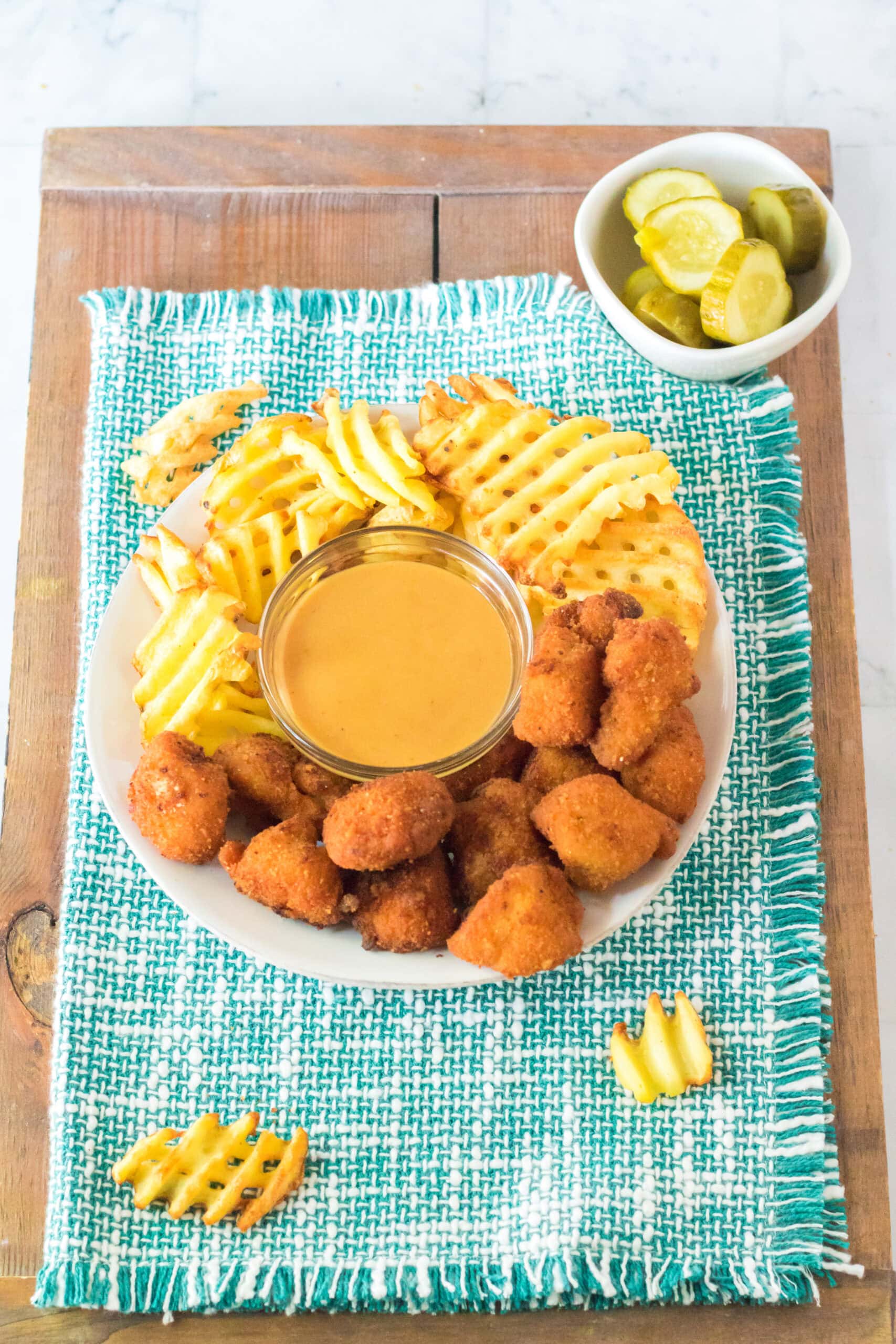 Chick Fil A sauce all made up in a bowl, and on a plate is Chick Fil A nuggets and waffle fries, a tea towel under the plate