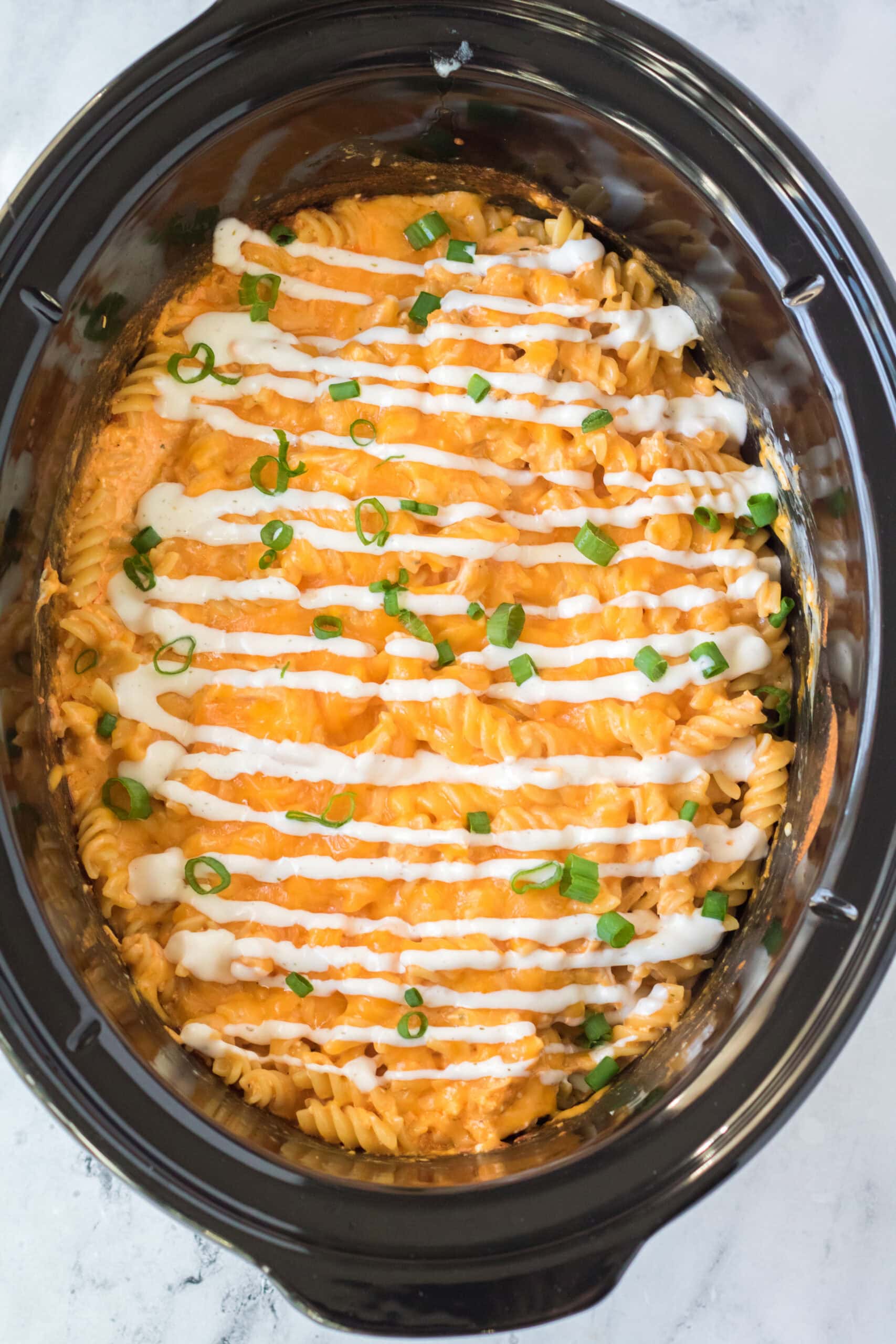 Last process to make crockpot buffalo mac chicken by adding ranch drizzle and green onion