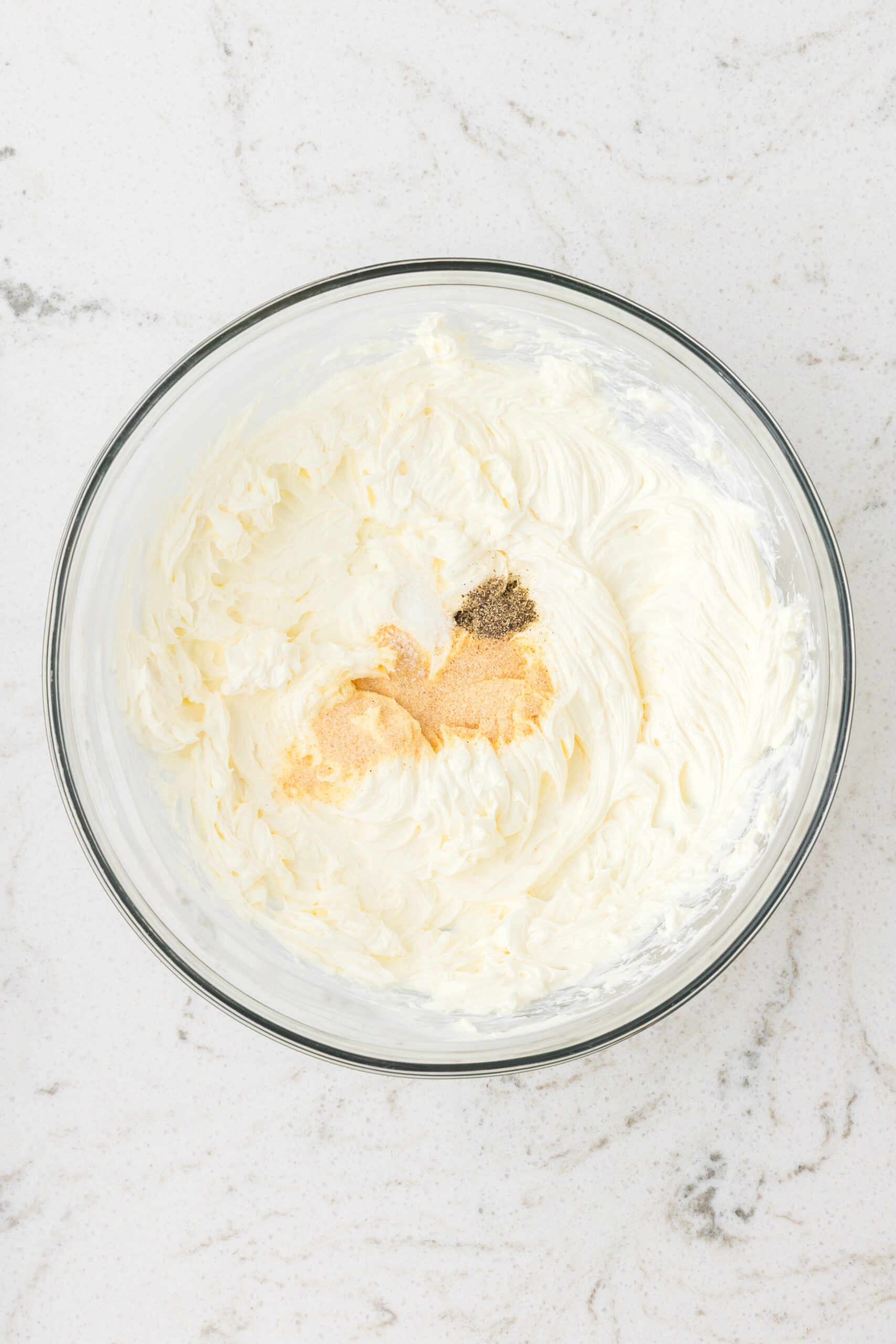 Adding garlic and onion powder with salt and pepper in the cream cheese in a bowl