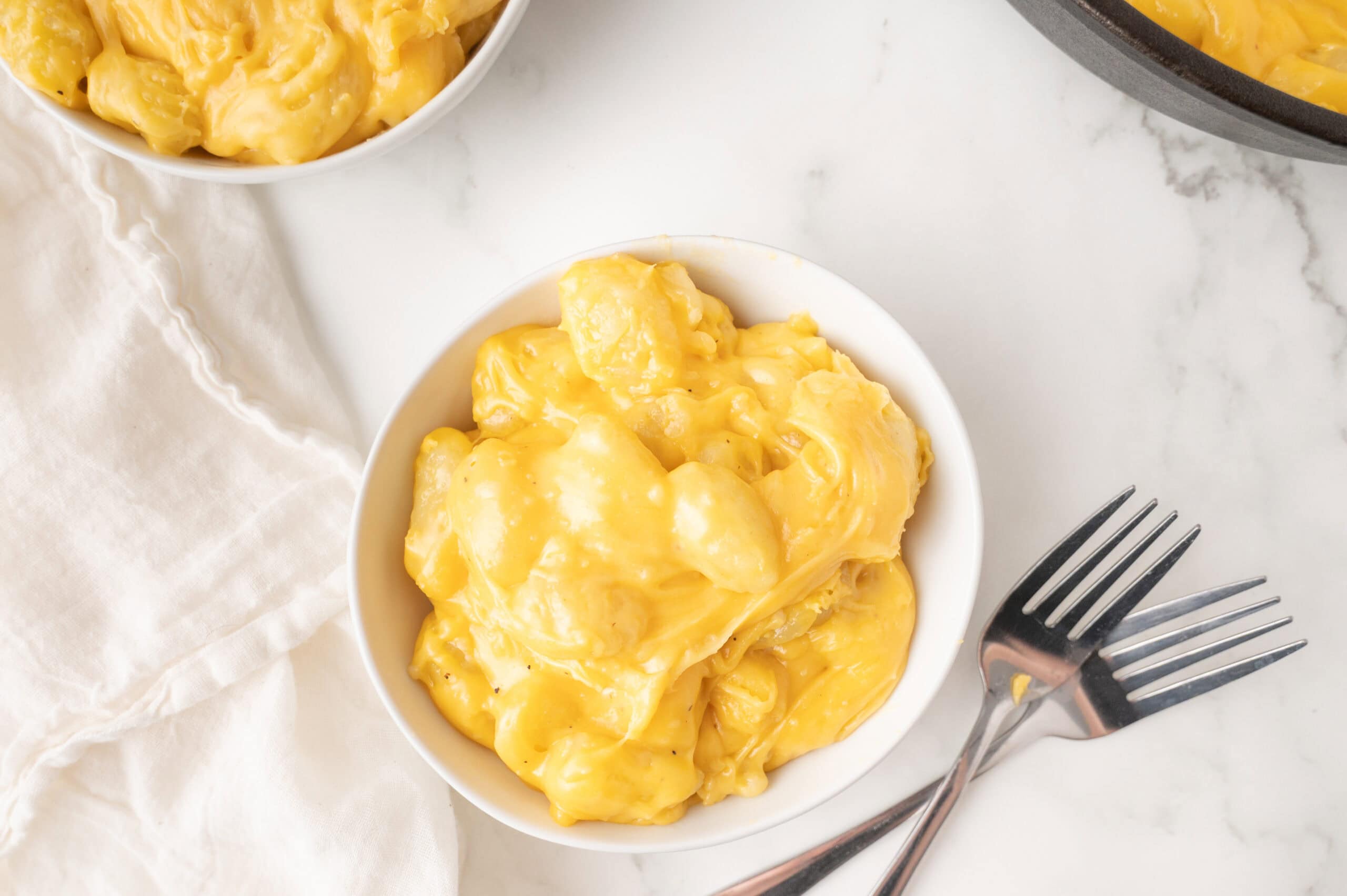 A white bowl full of gnocchi mac and cheese with forks to start enjoying