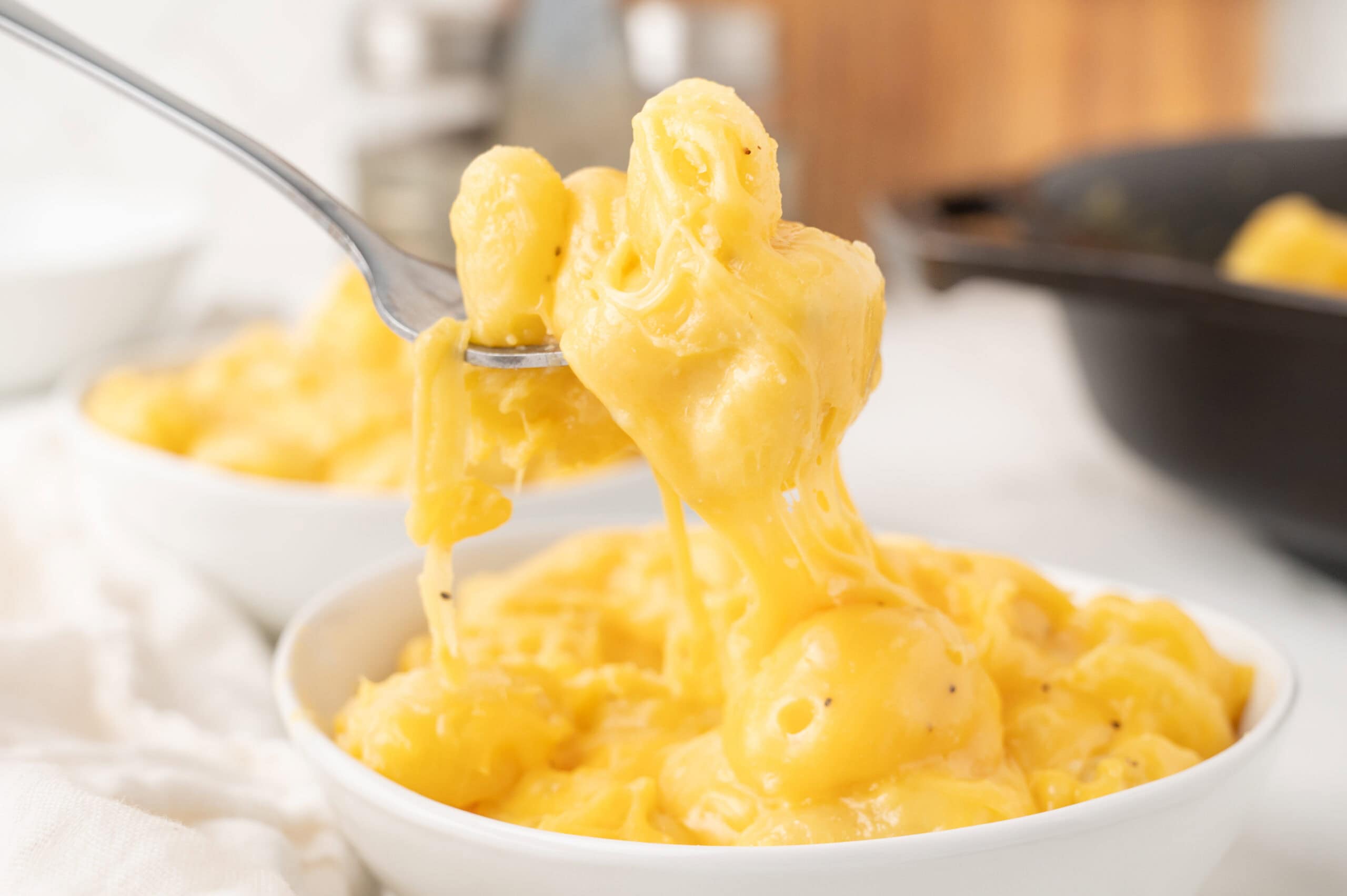 Fork holding up cheesy gnocchi from a bowl