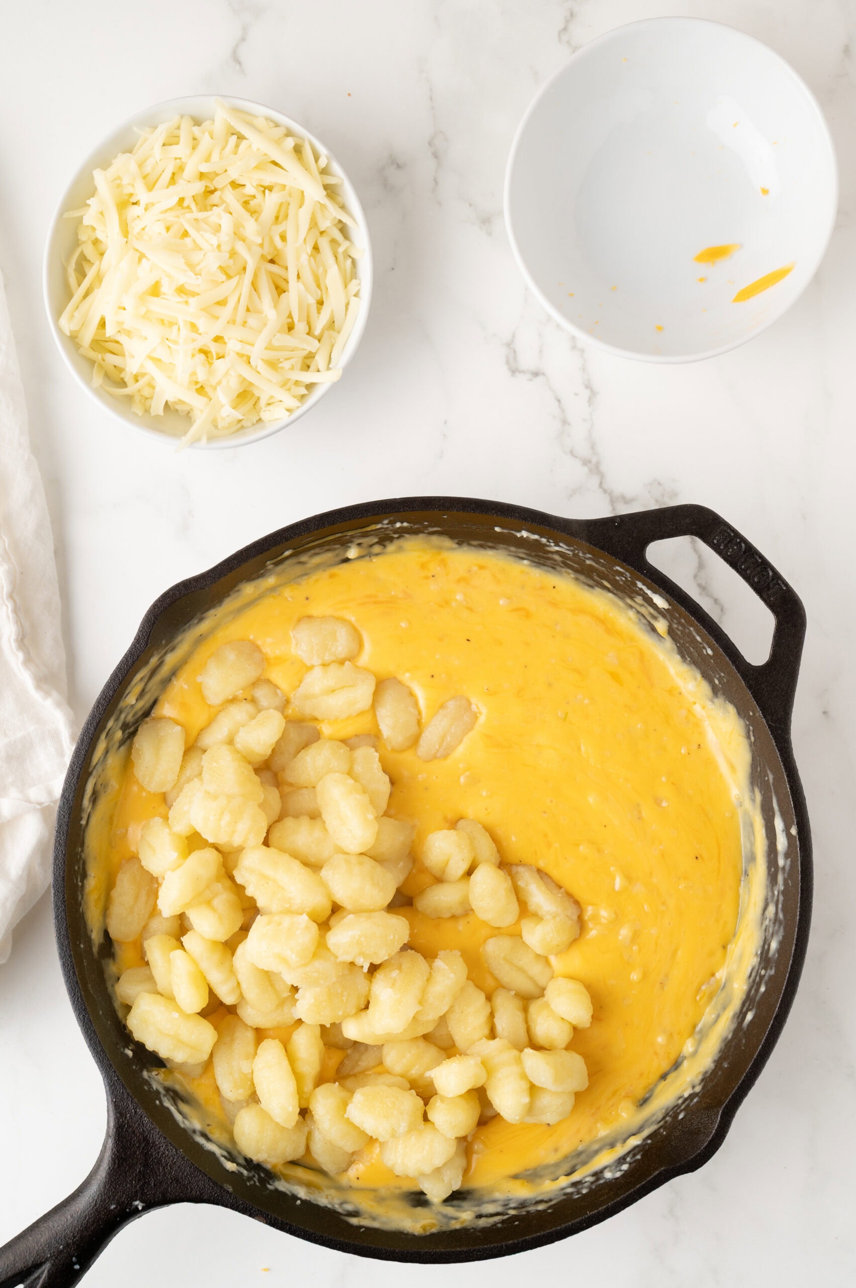Adding the cooked gnocchi to the roux being made in the cast iron pan
