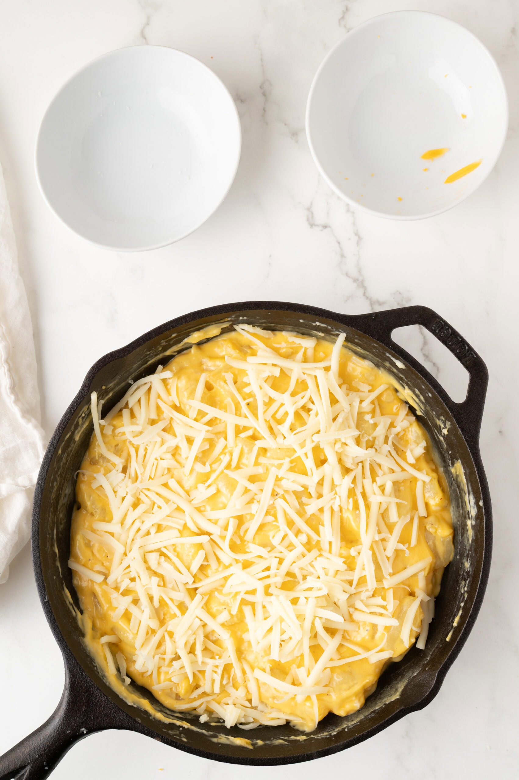 Adding shredded cheese to the cooked gnocchi