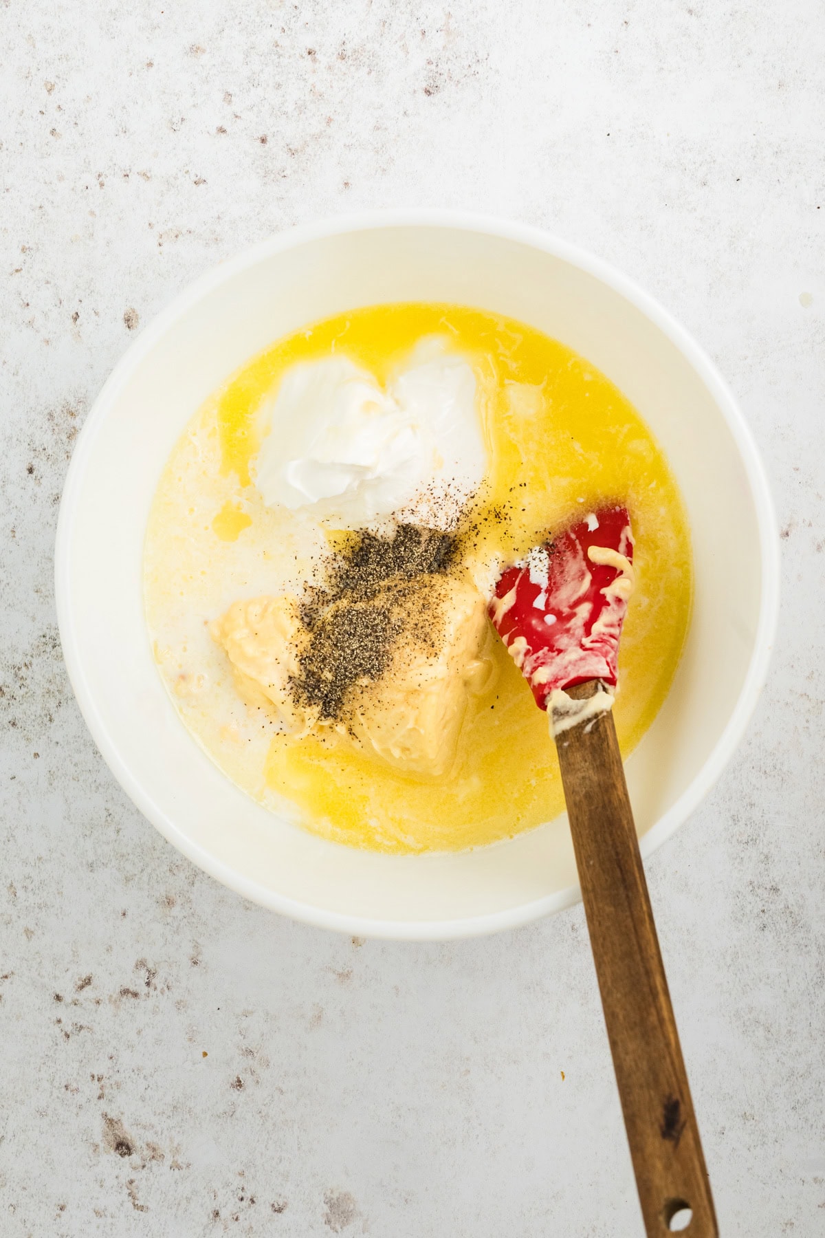 In a small bowl is melted butter, cream of chicken soup, sour cream, milk, salt and pepper with a spatula to mix together