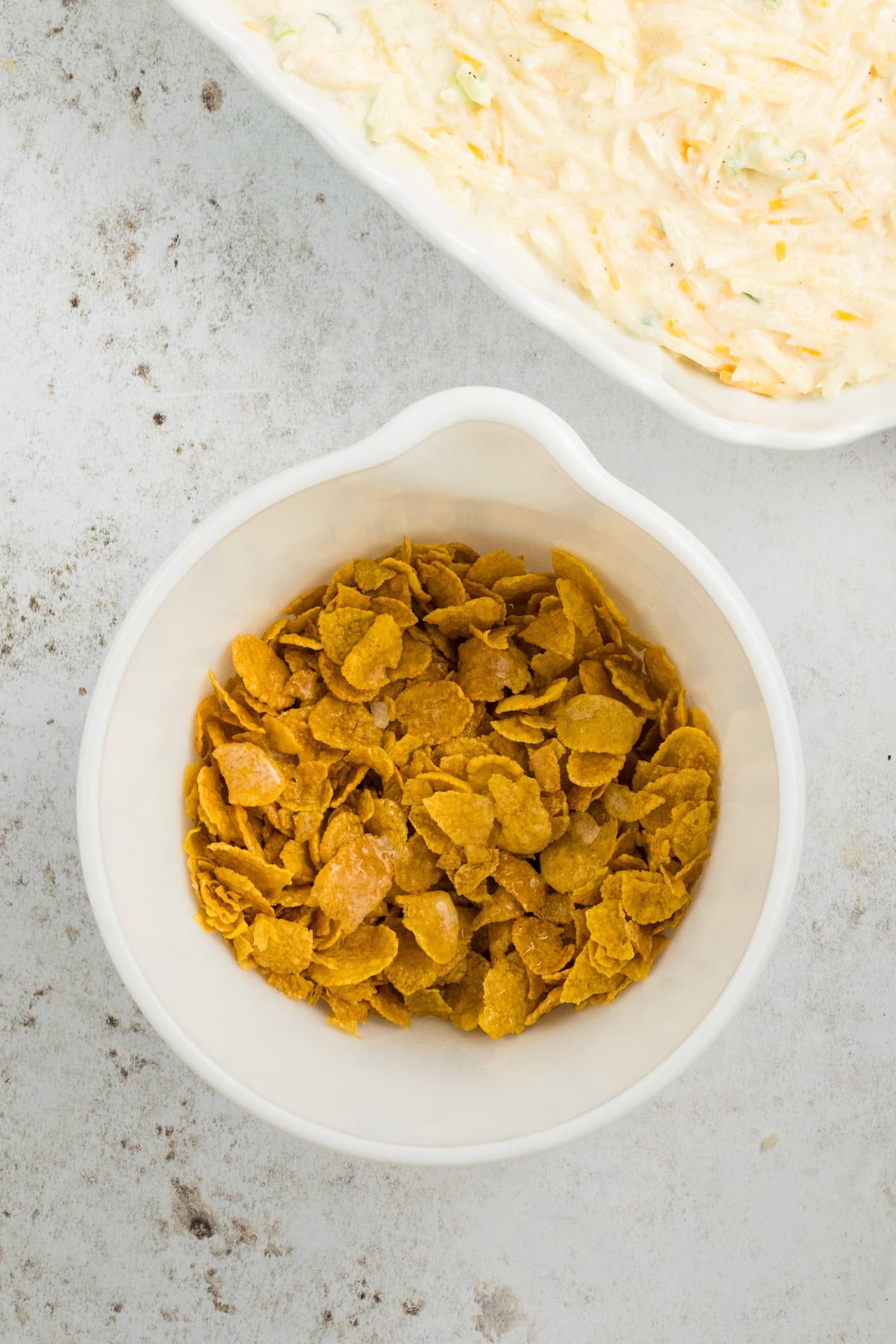 Corn flake topping with melted butter ready to sprinkle over potato mixture in baking dish