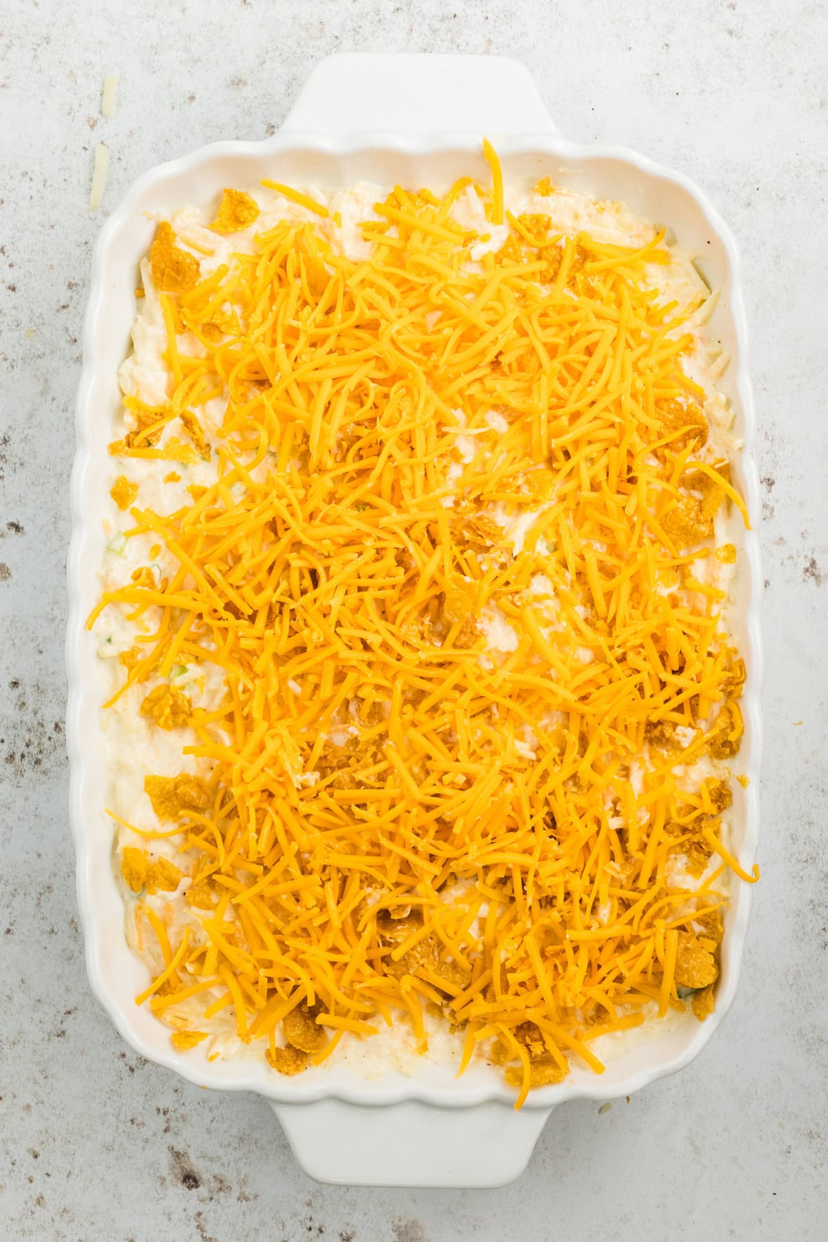 Adding cheddar cheese on top of potato mix in baking dish