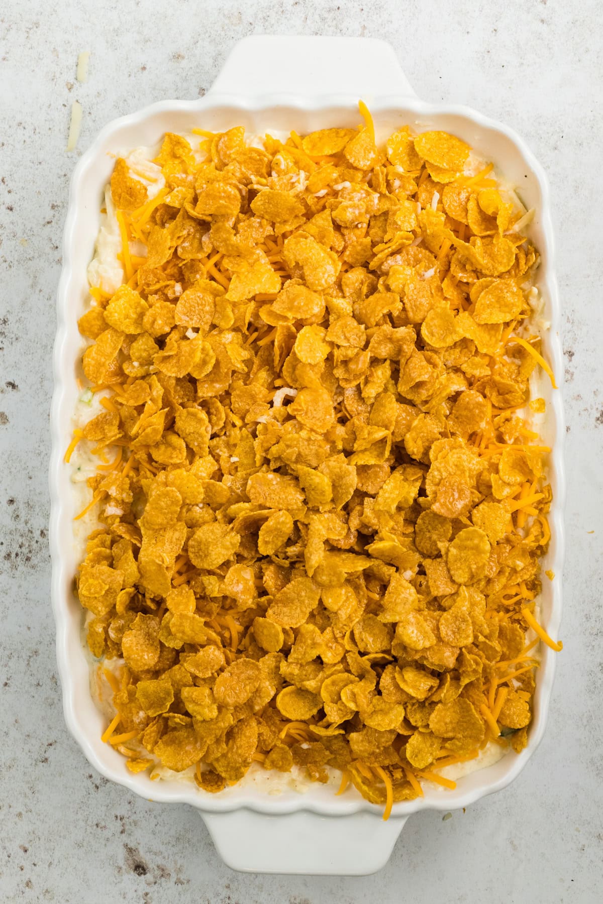 All ingredients to make cheesy potatoes in baking dish, ready to be cooked.