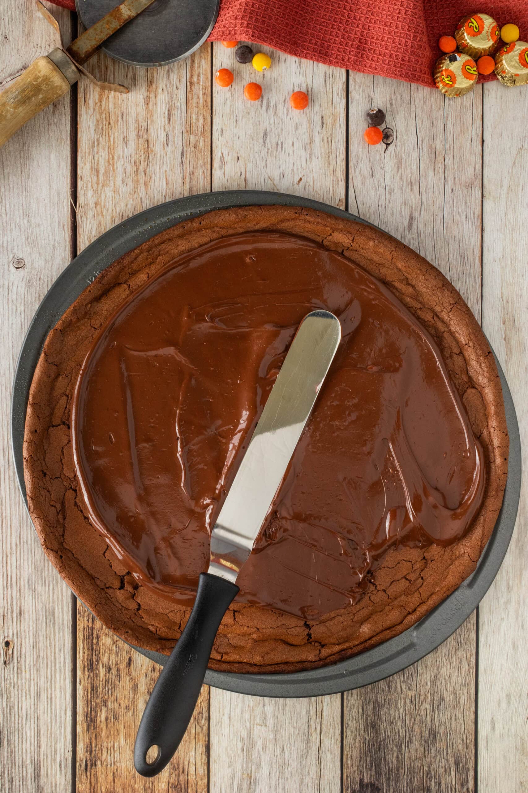 Spreading ganache on top off brownie pizza