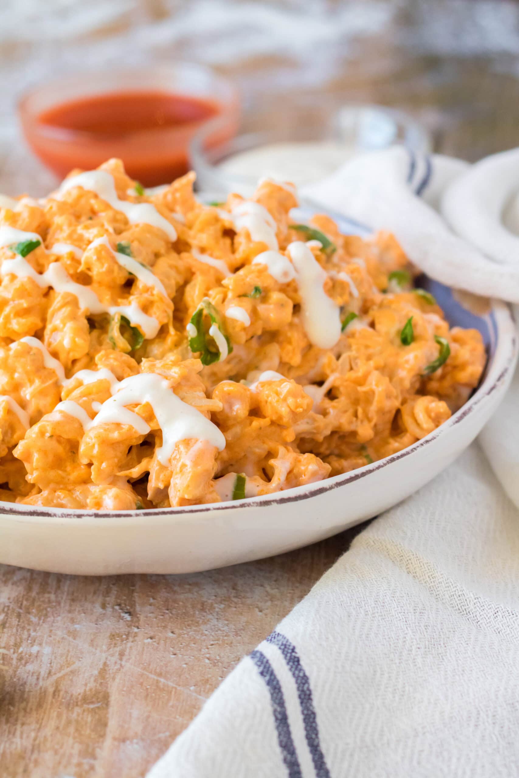Crockpot buffalo mac n cheese in a bowl, with green onions and ranch drizzle