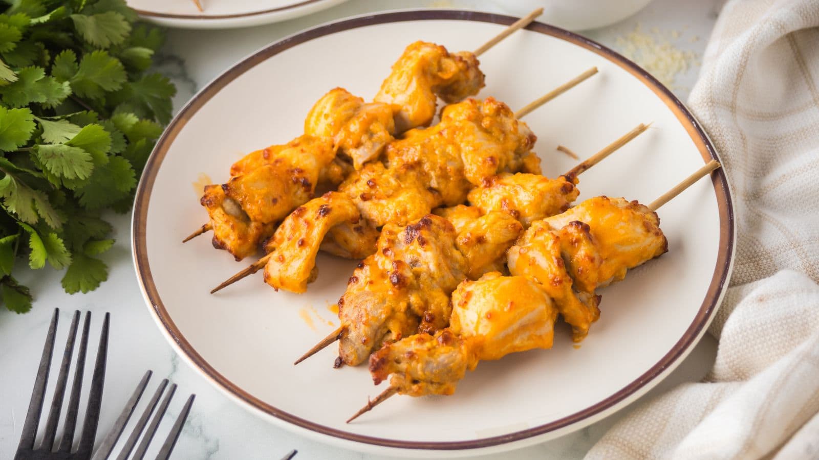 air fryer buffalo chicken thighs on skewers on a white plate