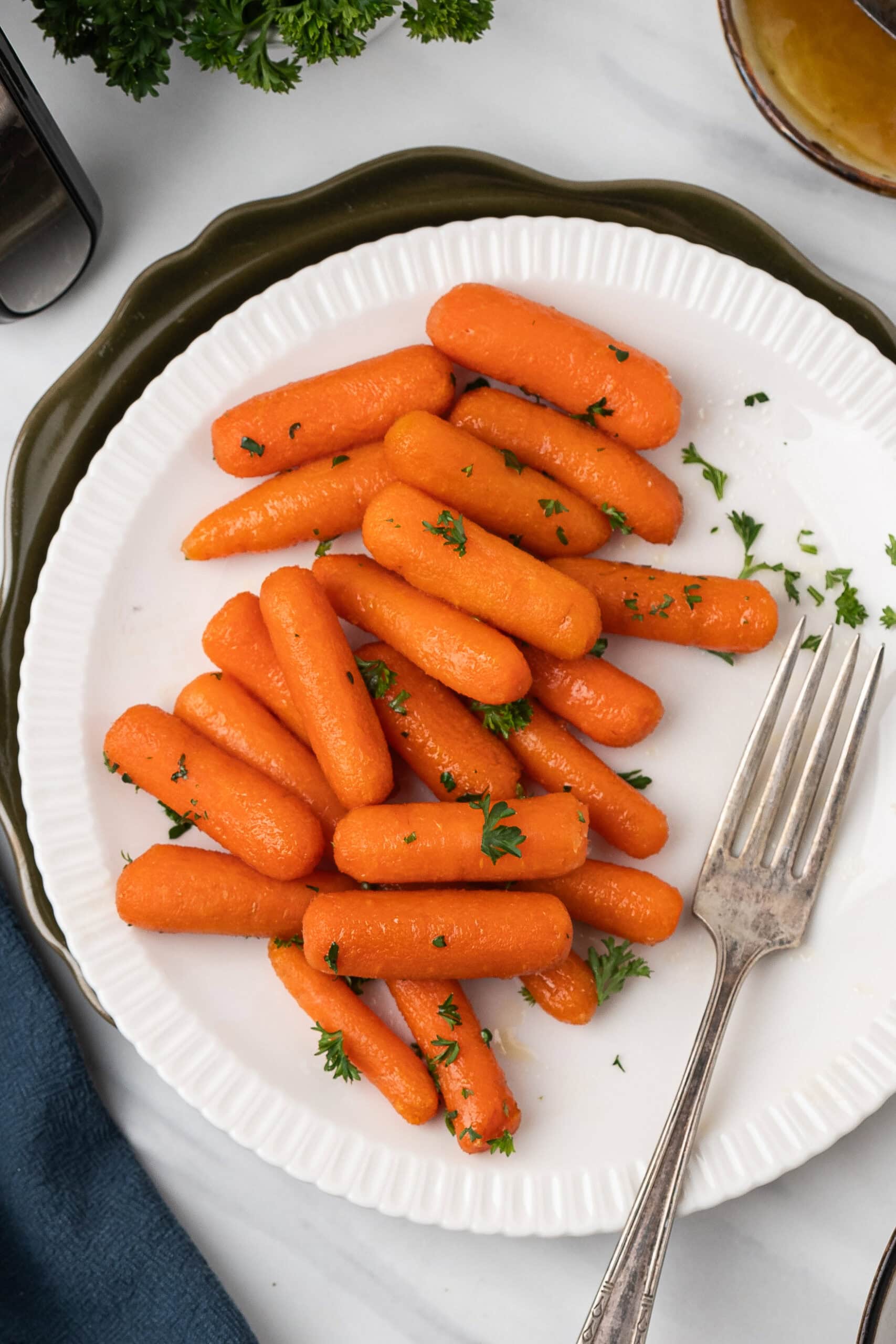 Air fryer baby carrots piled on a plate with fresh parsley