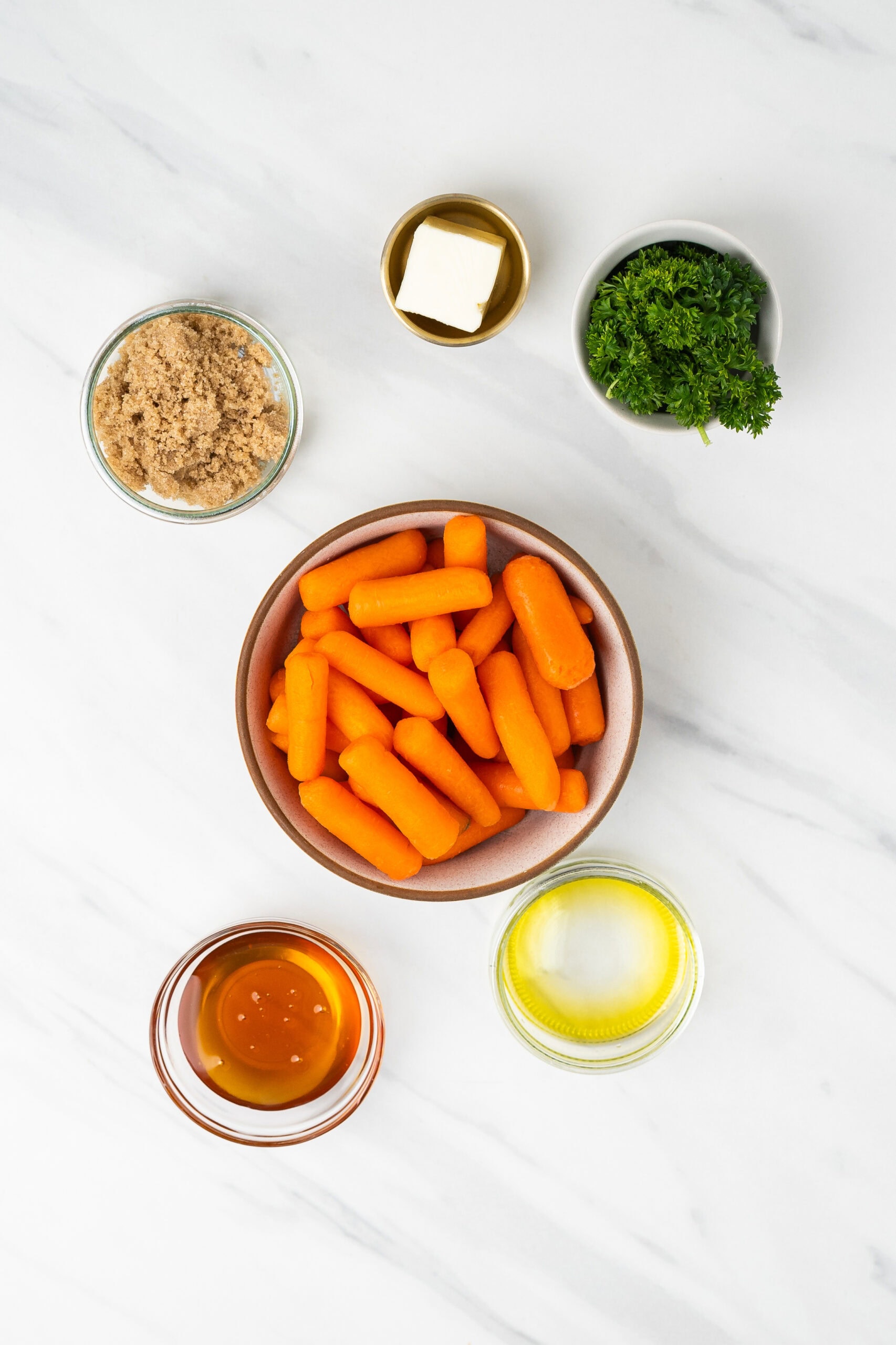 All ingredients for air fryer carrots: butter, honey, baby carrots, brown sugar, fresh parsley,
