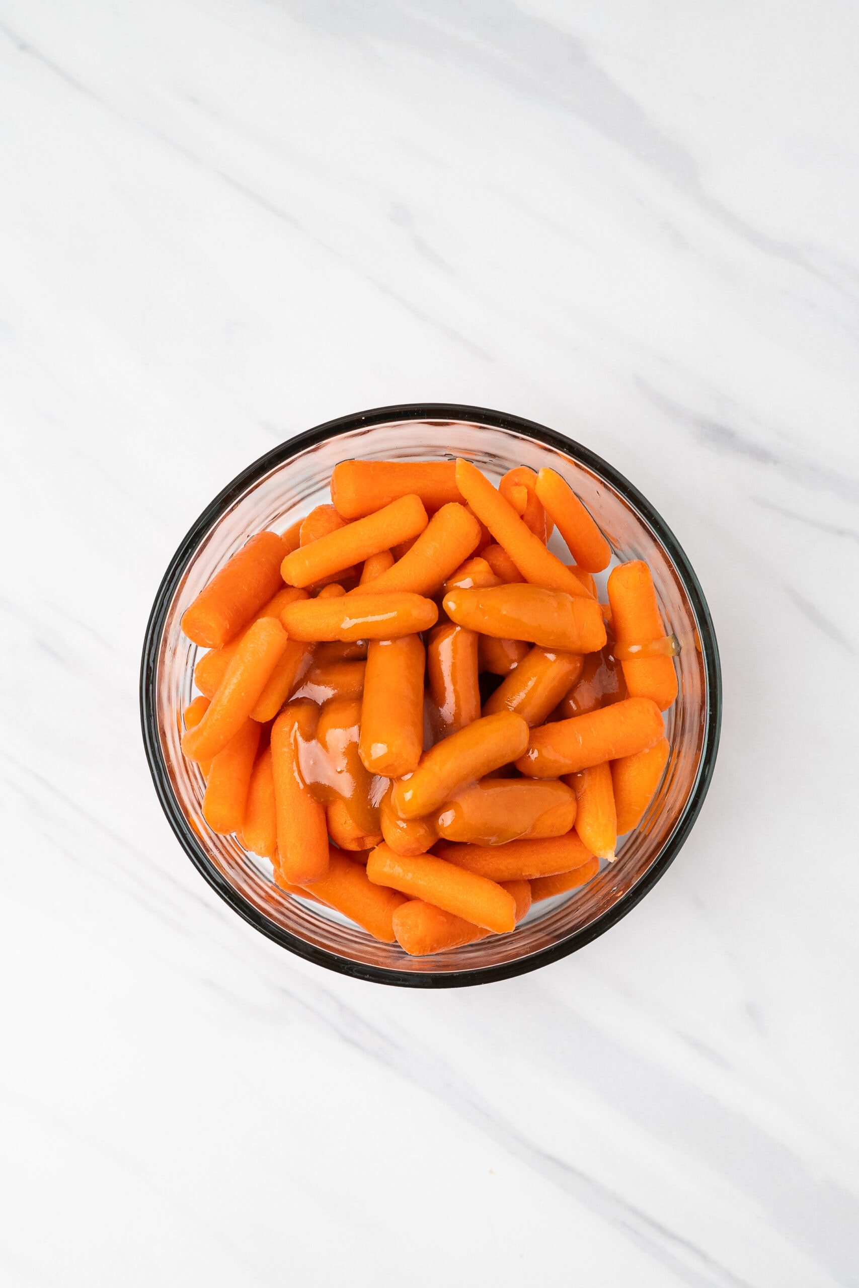 Carrots in glass bowl with the glaze on top, ready to be stirred