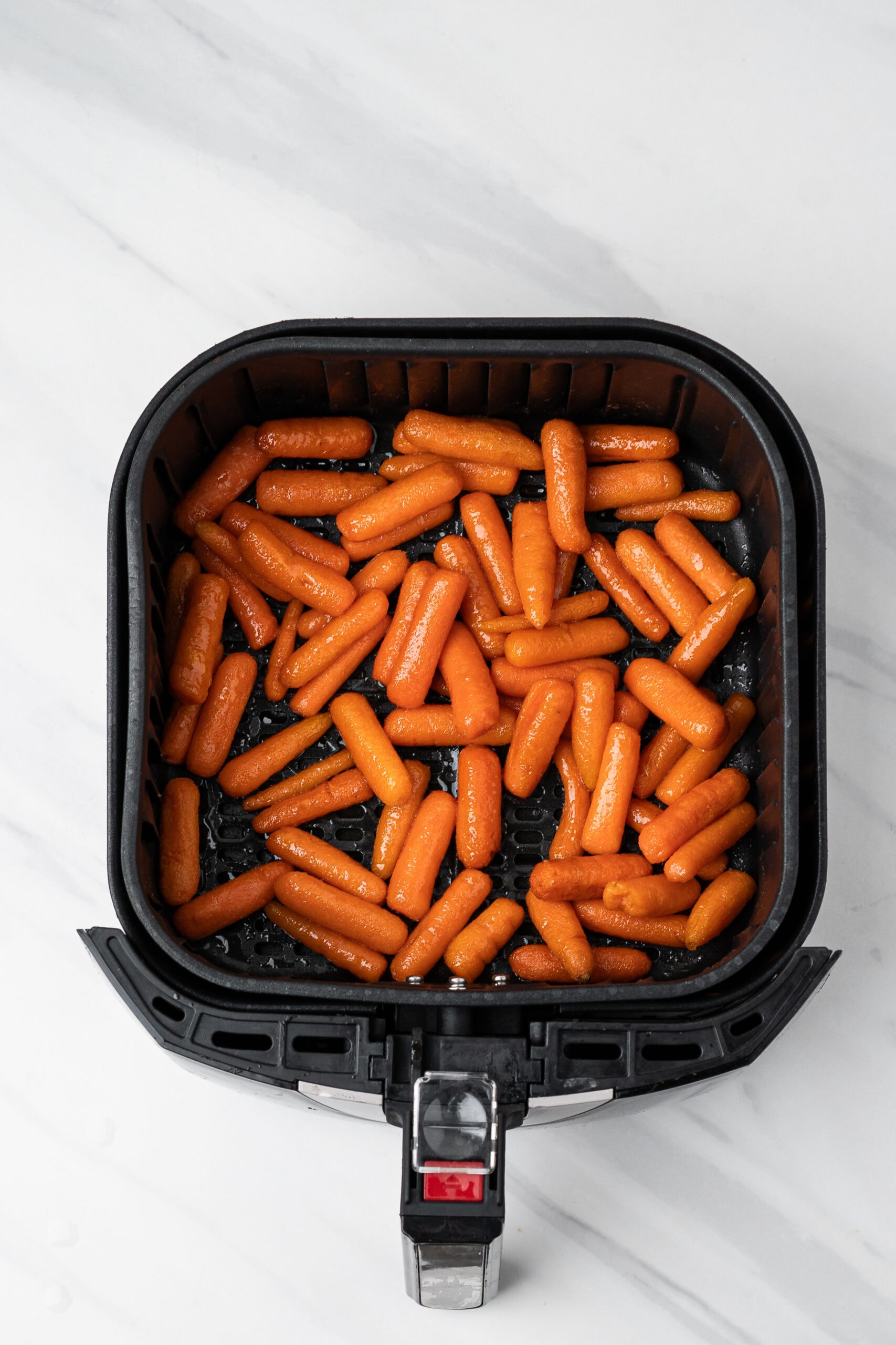 Baby carrots in air fryer, coated and ready to be cooked