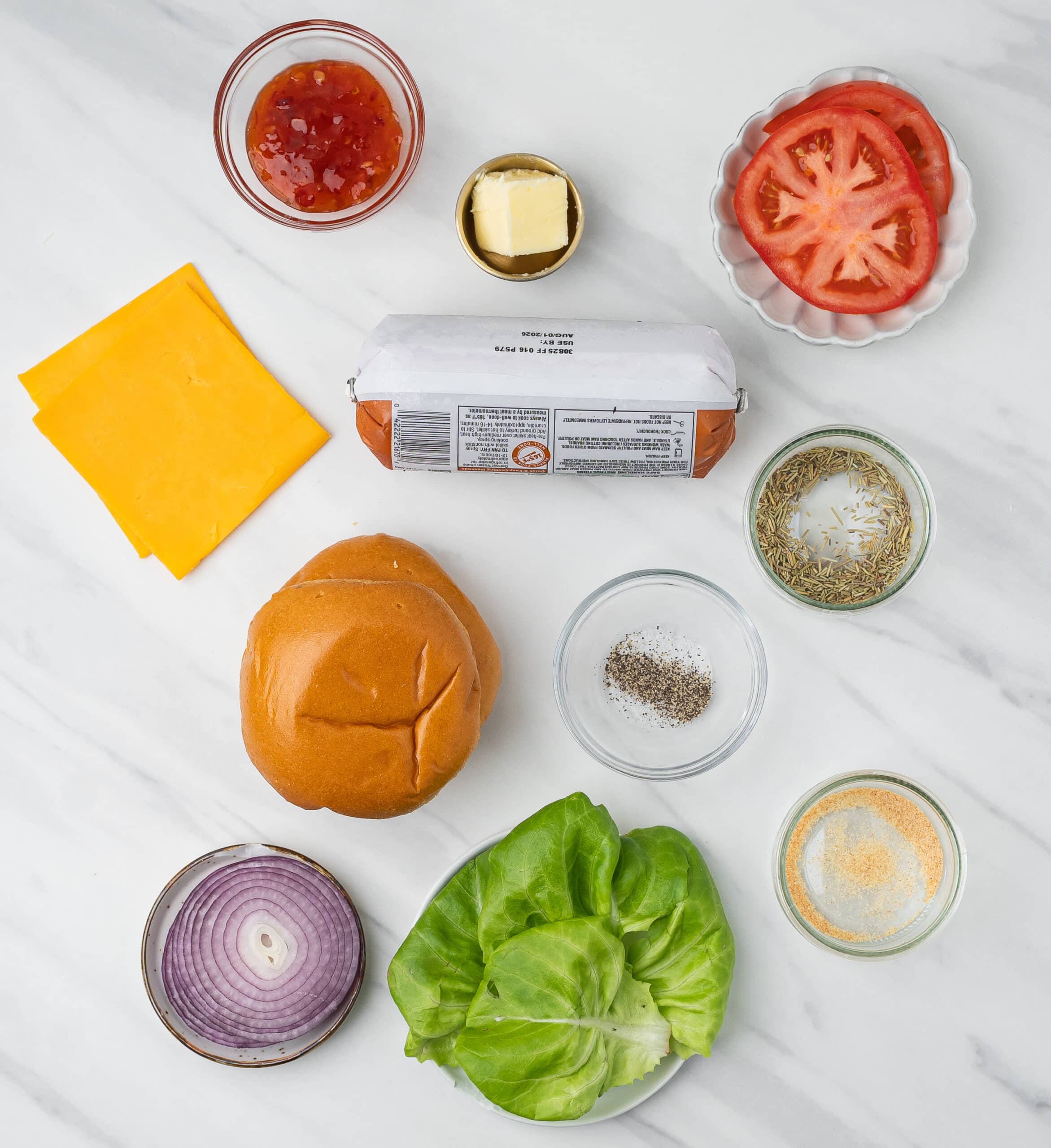 Ingredients to make air fryer turkey burgers: ground turkey, lettuce, red onion, garlic powder, salt & pepper, dried rosemary, brioche buns, tomato slices, cheddar cheese slices, butter