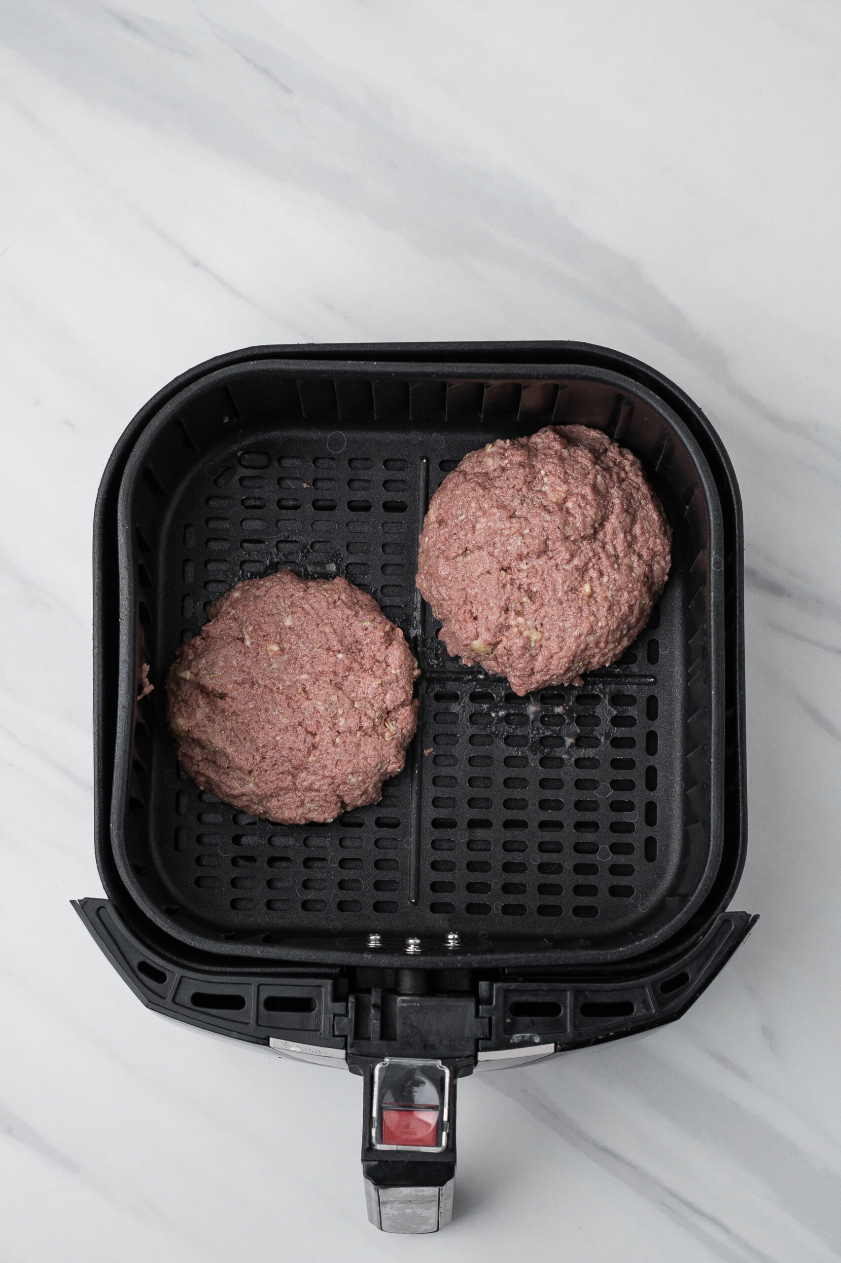 Turkey burgers all made up and placed, with space, in the air fryer, ready to be cooked.