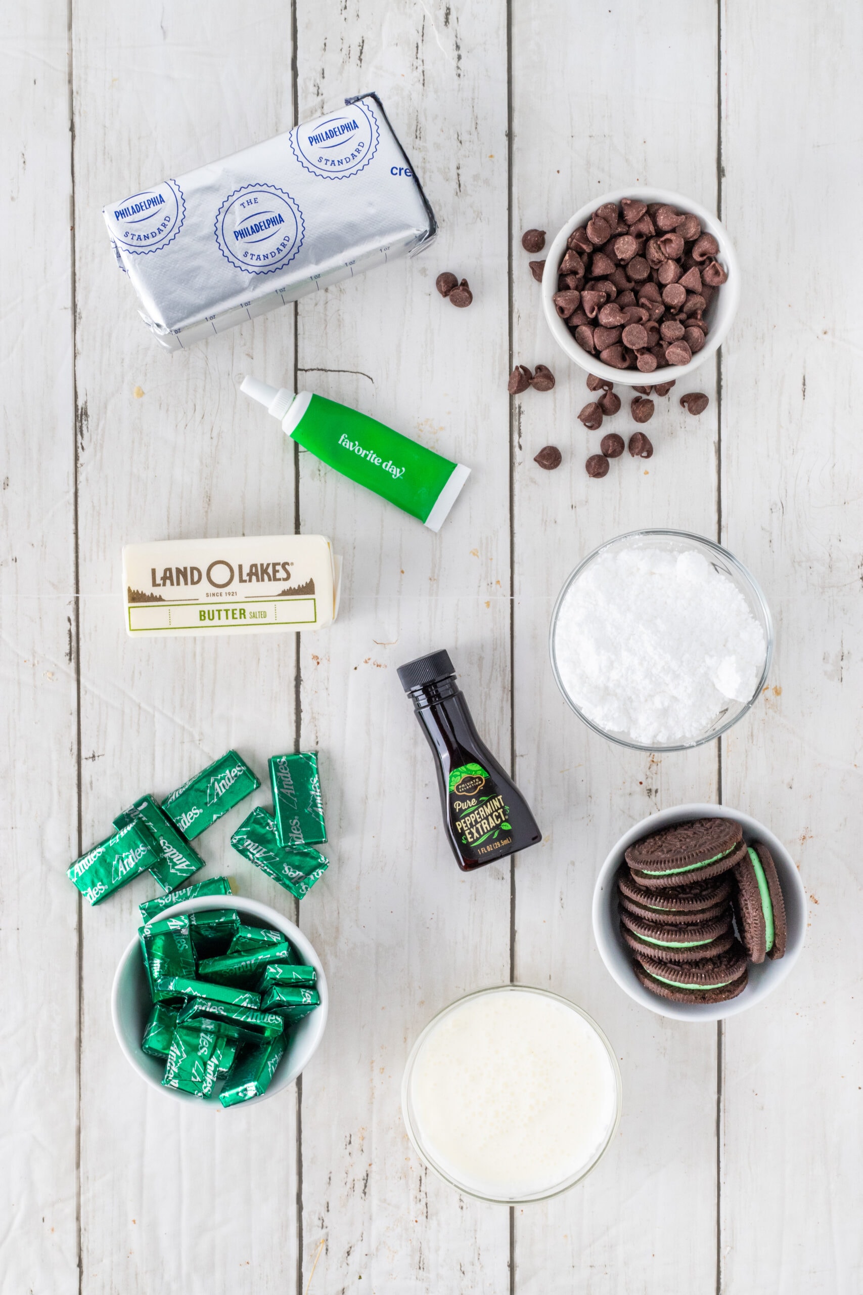 Andes Cheesecake ingredients: Andes mint chocolates, heavy cream, mint oreos, melted butter, chocolate chips, peppermint extract, green food coloring, cream cheese and powdered sugar
