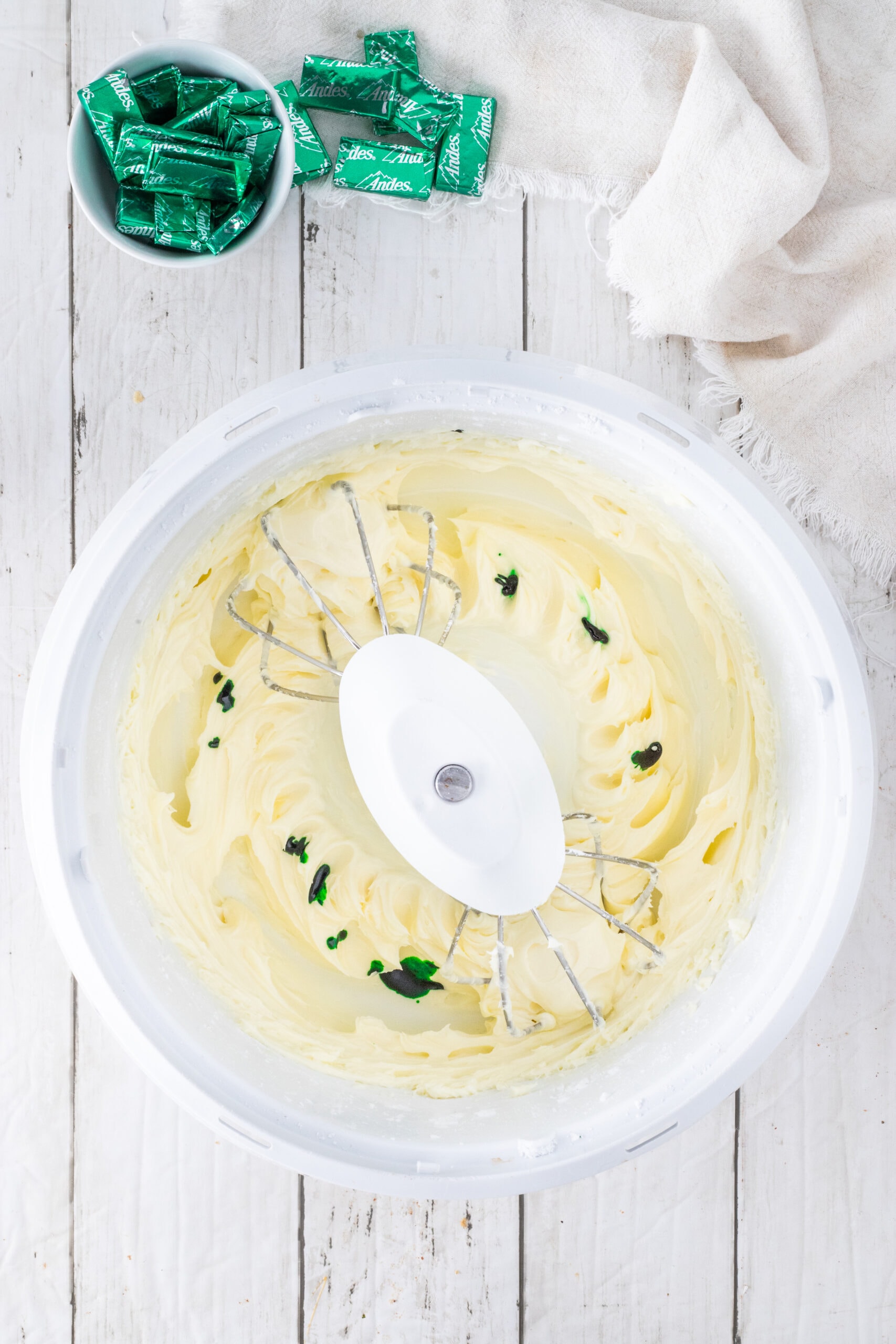 Beating softened cream cheese with powdered sugar, adding in green food coloring
