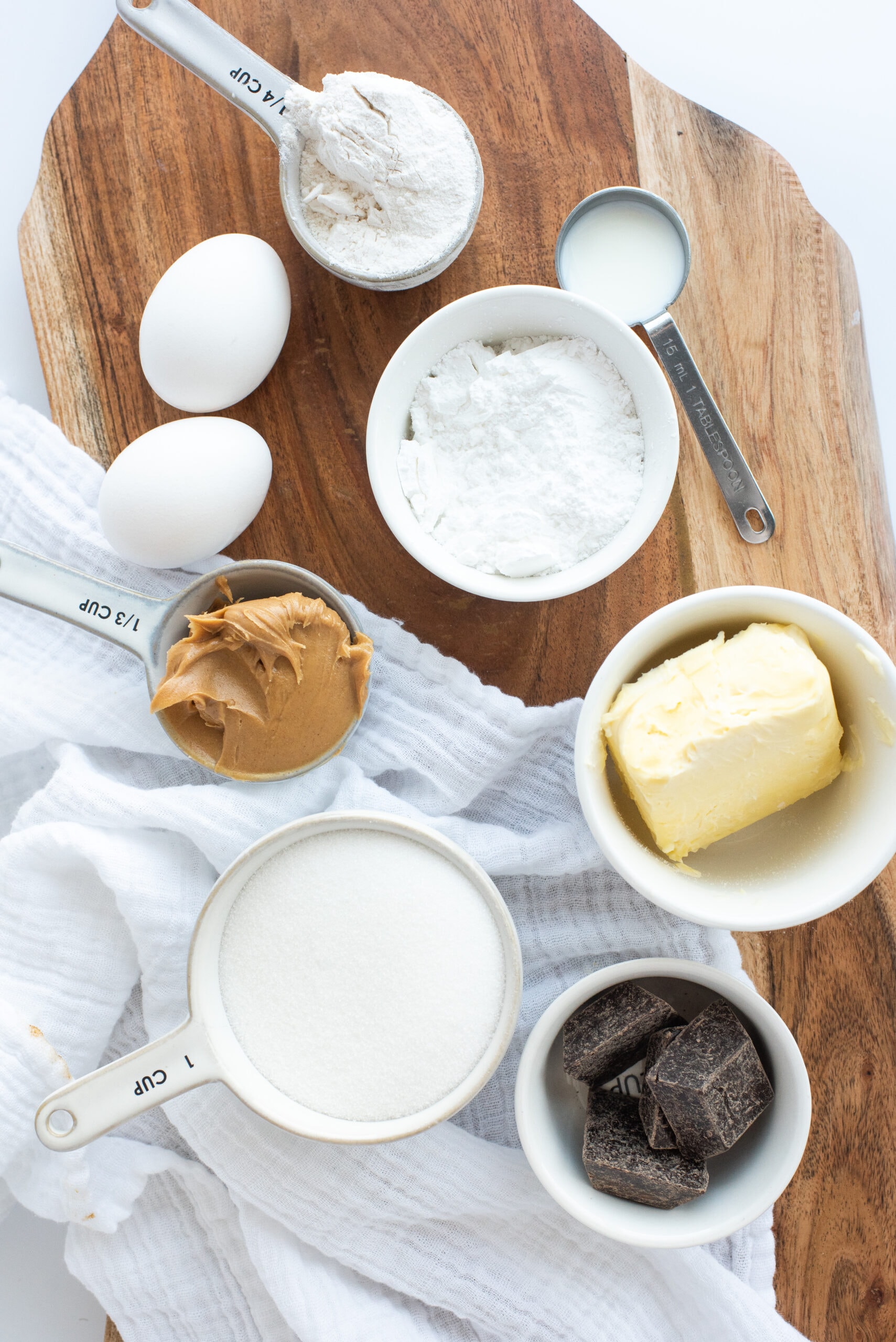All ingredients pictured to make brownies with peanut butter frosting: chocolate squares, butter, powdered sugar, peanut butter, eggs, flour, sugar and milk, semi-sweet chocolate