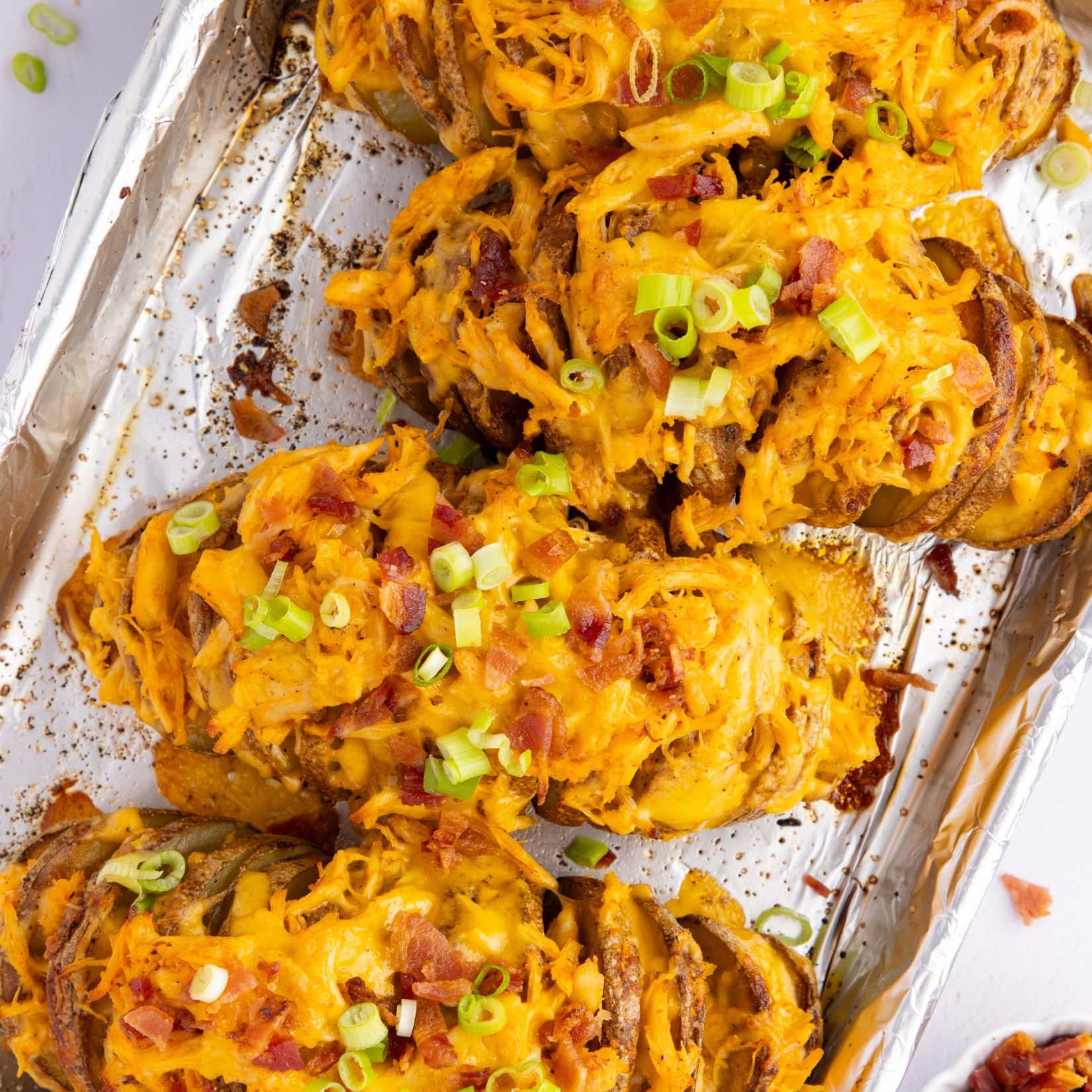 Stuffed buffalo chicken potatoes topped with green onion and bacon on a sheet pan