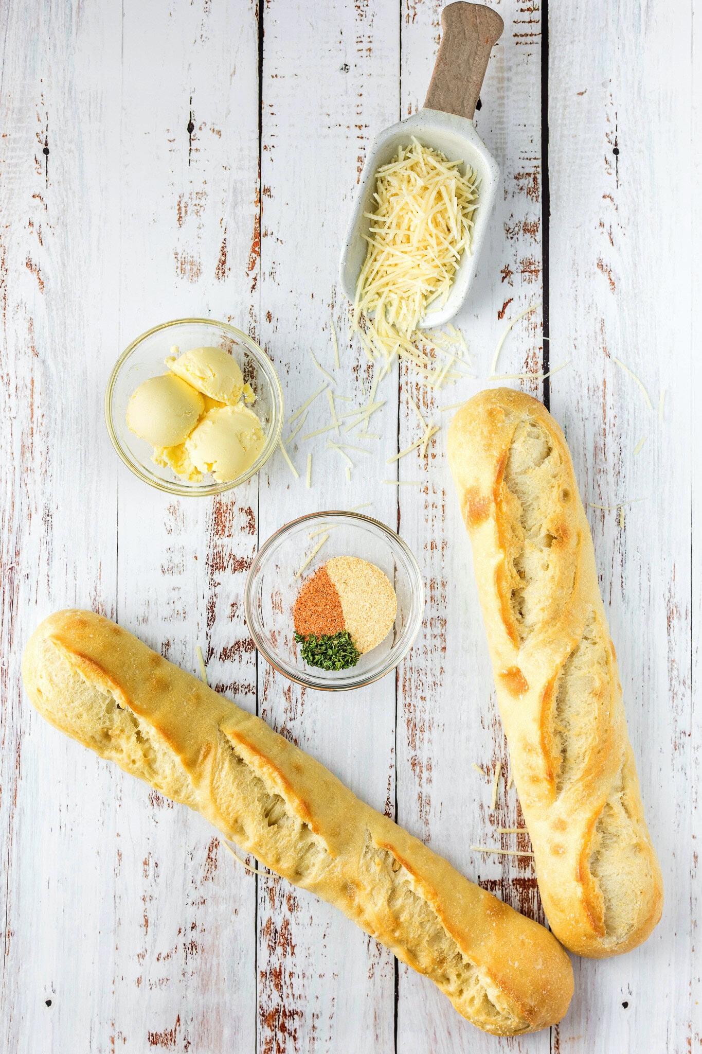 Ingredients to make cheesy bread: french bread, butter, cajun seasoning, dried parsley, and parmesan cheese