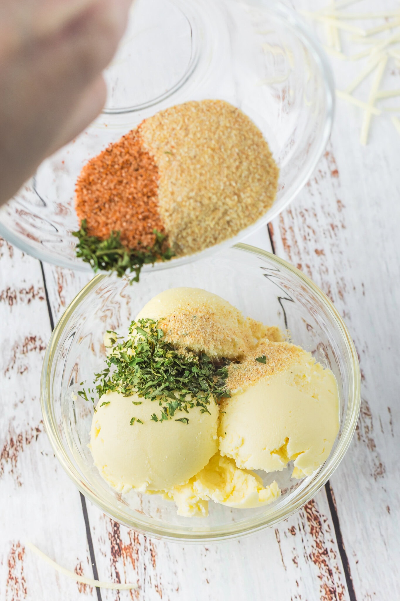 Adding the spices to the butter in bowl: garlic powder, dried parsley, and cajun seasoning