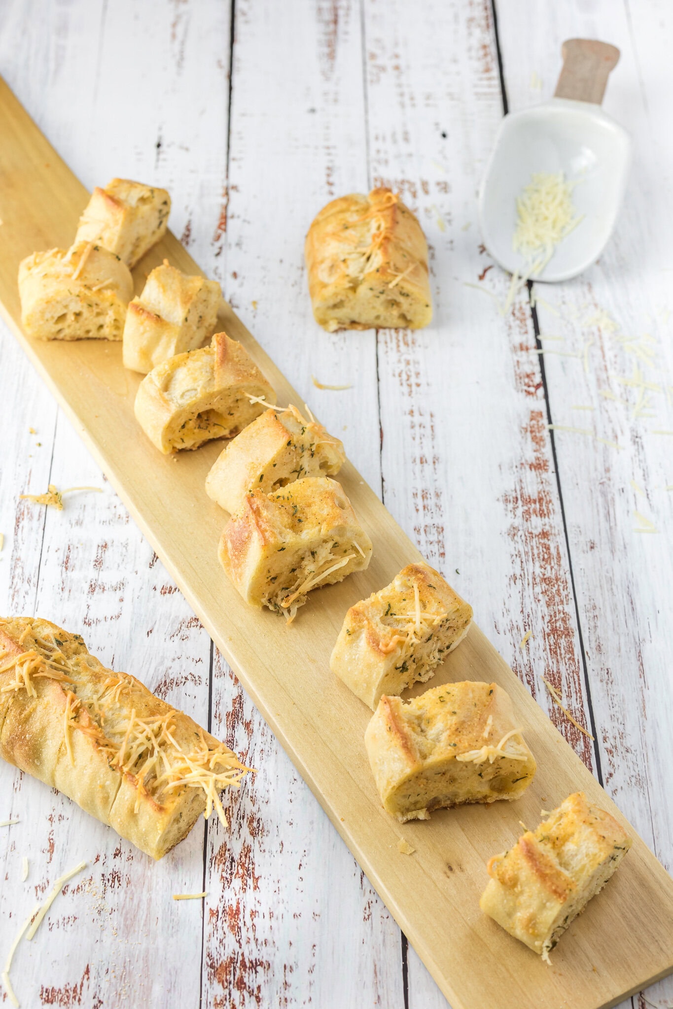 Cheesy bread is cut into slices on a wooden board