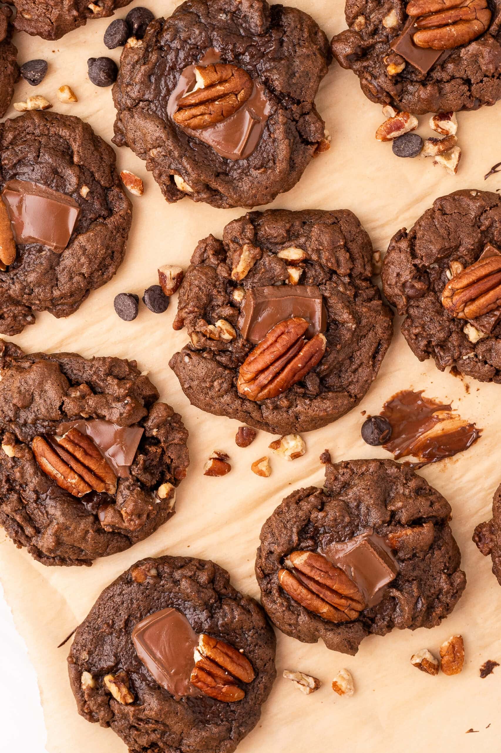 Chewy double chocolate pecan cookies are spread apart on parchment paper