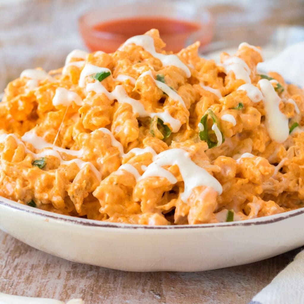 crockpot buffalo chicken mac and cheese drizzled with ranch dressing in a white bowl