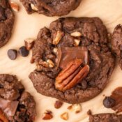 Close up of a chewy double chocolate pecan cookie on parchment paper