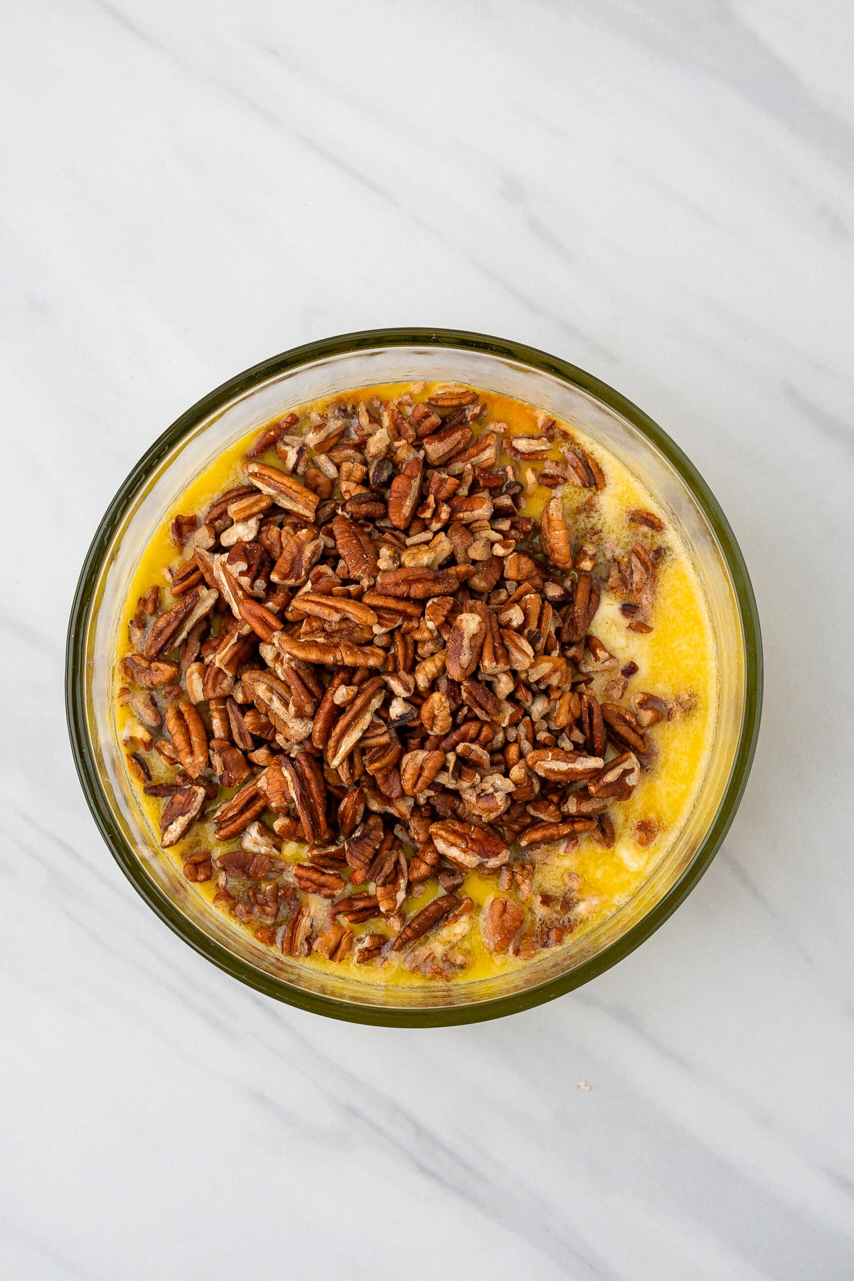 Melted butter, salt and pecans in a mixing bowl
