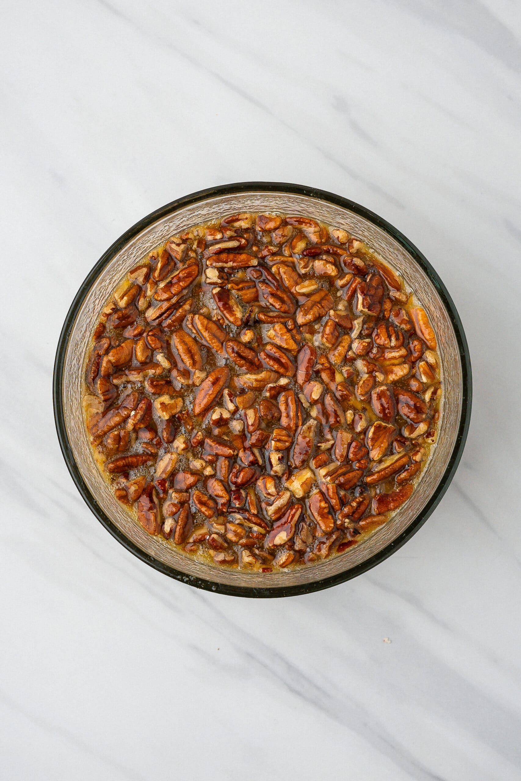 In a mixing bowl is eggs, corn syrup. sugar, pecans, melted butter and salt.