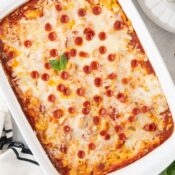 pepperoni pizza mac and cheese topped with melty mozzarella and mini pepperoni in a white baking dish