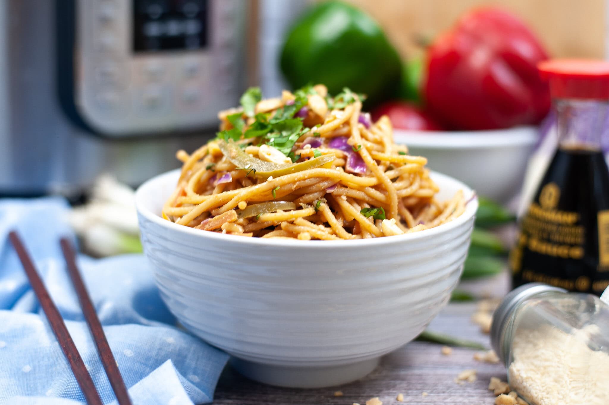 Spicy Thai peanut noodles in a bowl with chopsticks