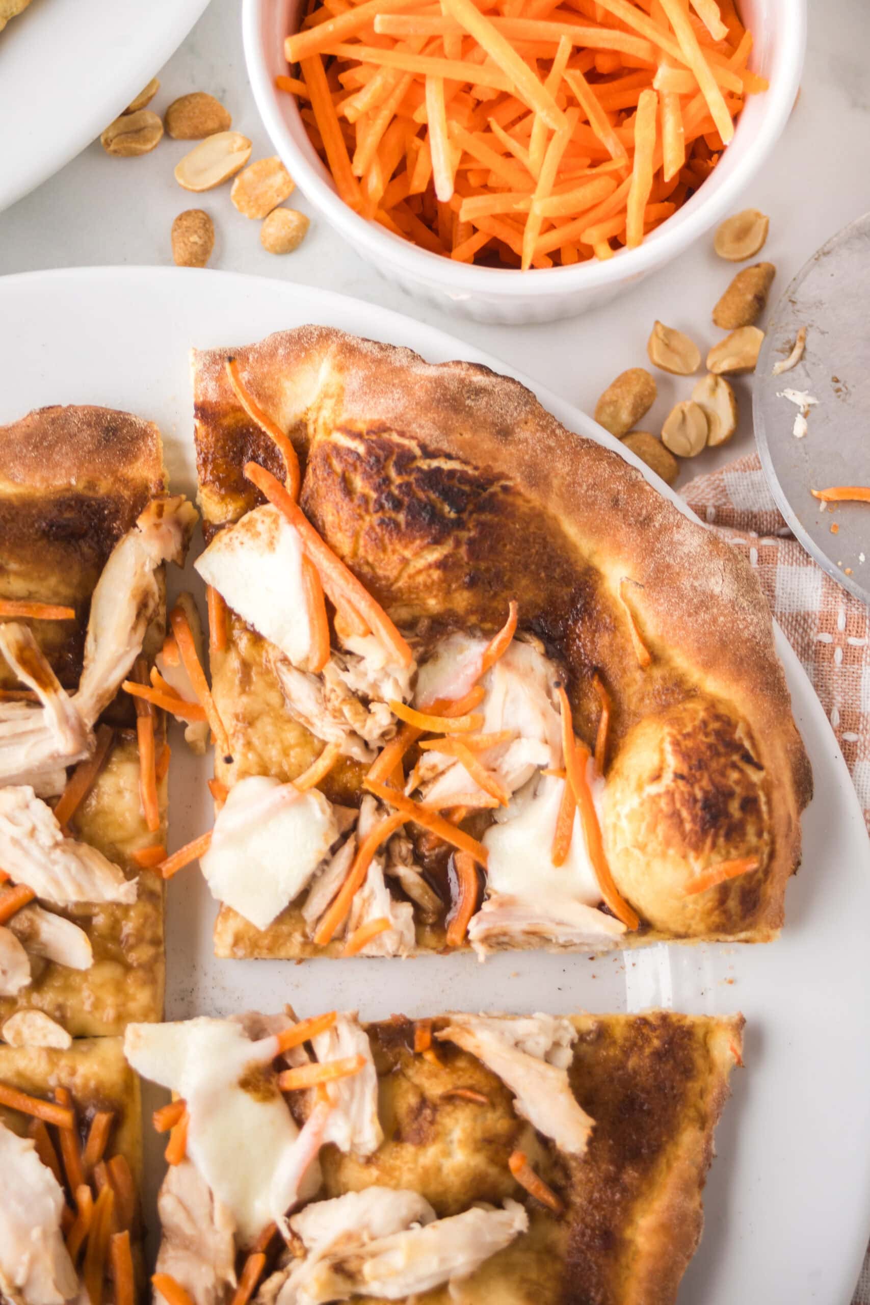 Thai chicken pizza is baked and a slice has been cut.