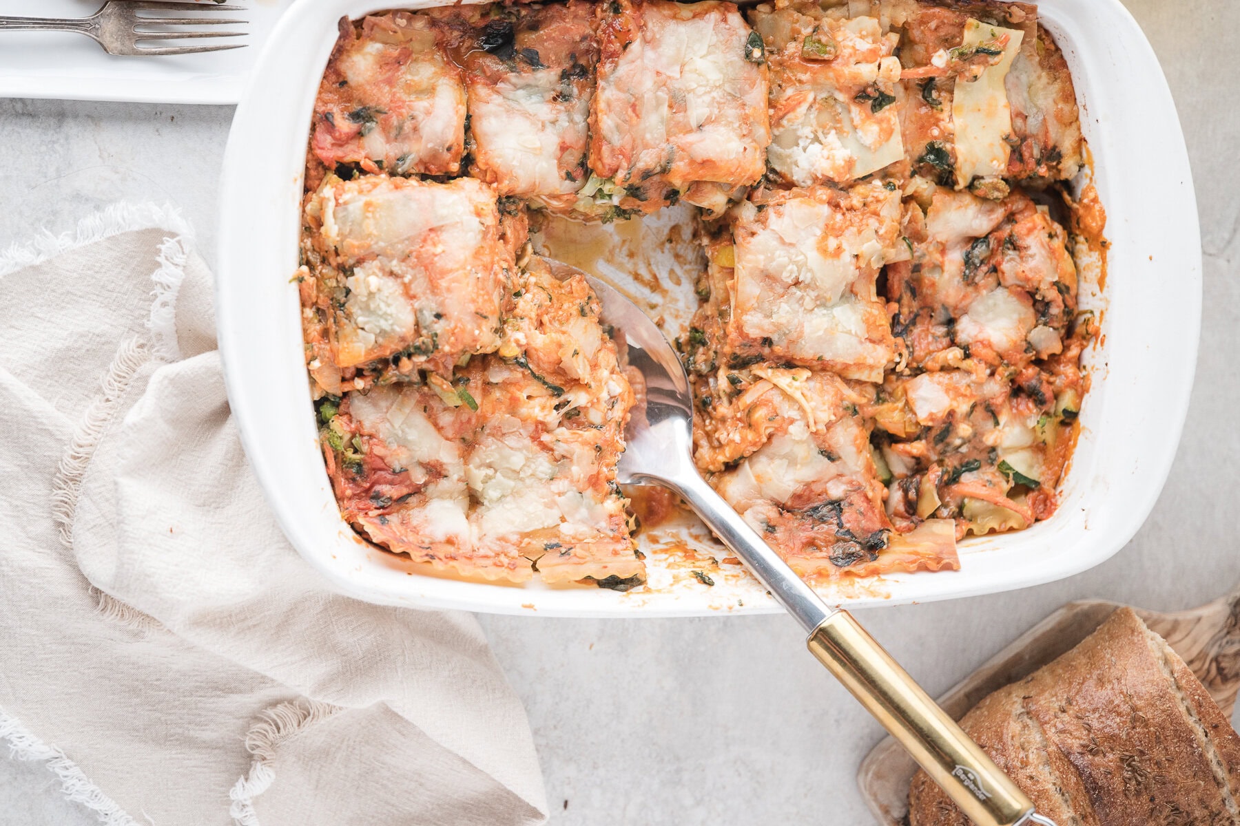 Veggie lasagna in baking dish, all baked and being scooped up to be served