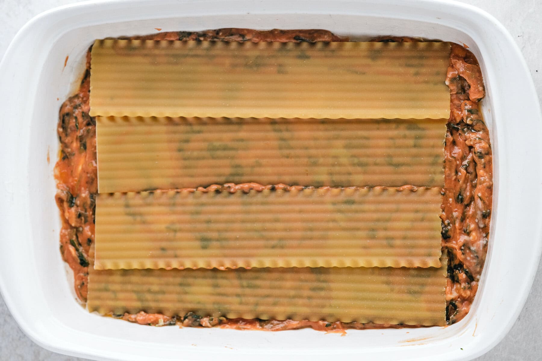 Lasagna noodles on top of spinach and spaghetti sauce mix