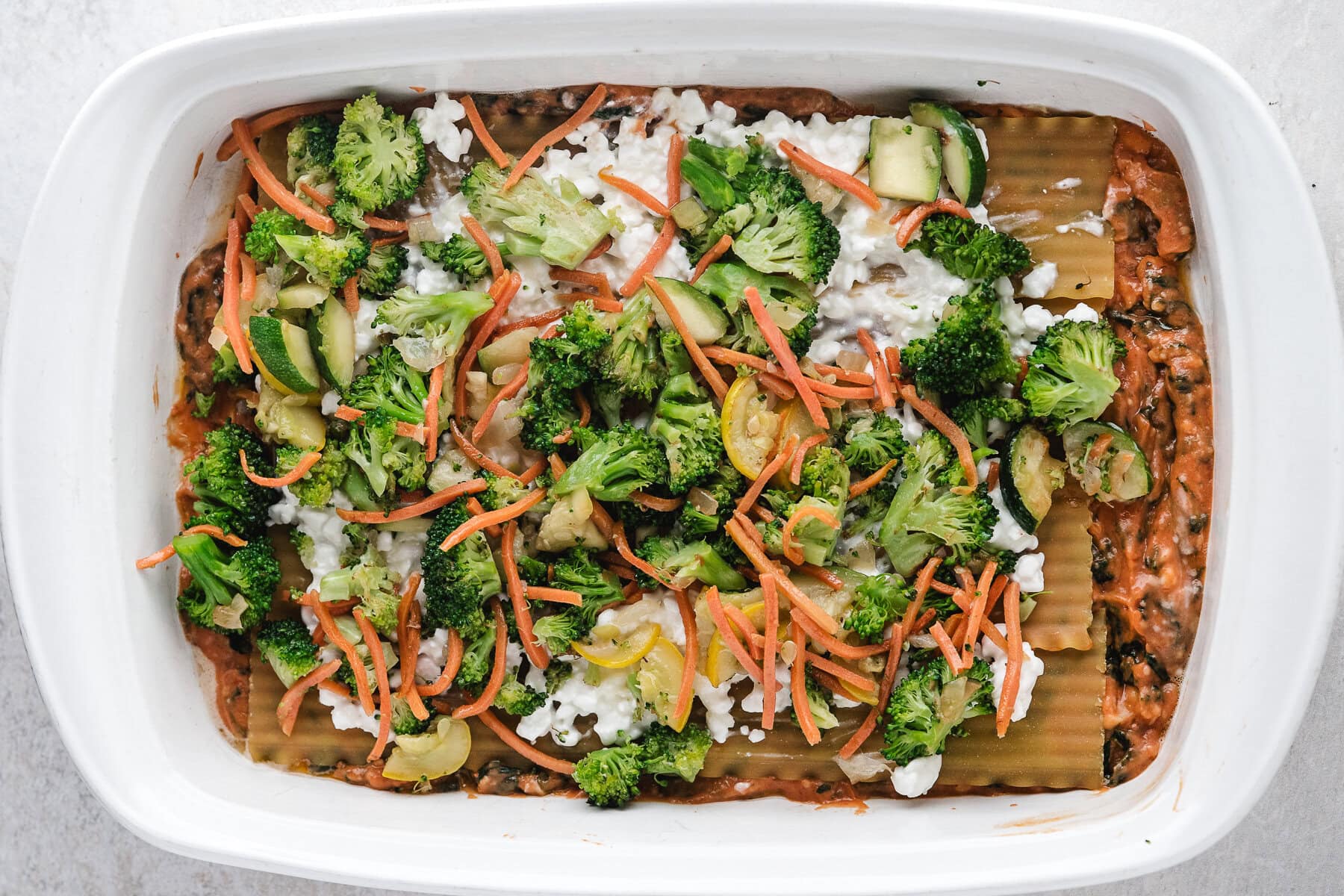 Vegetable layer of broccoli and carrots on top of cottage cheese layer, on top of lasagna noodles.