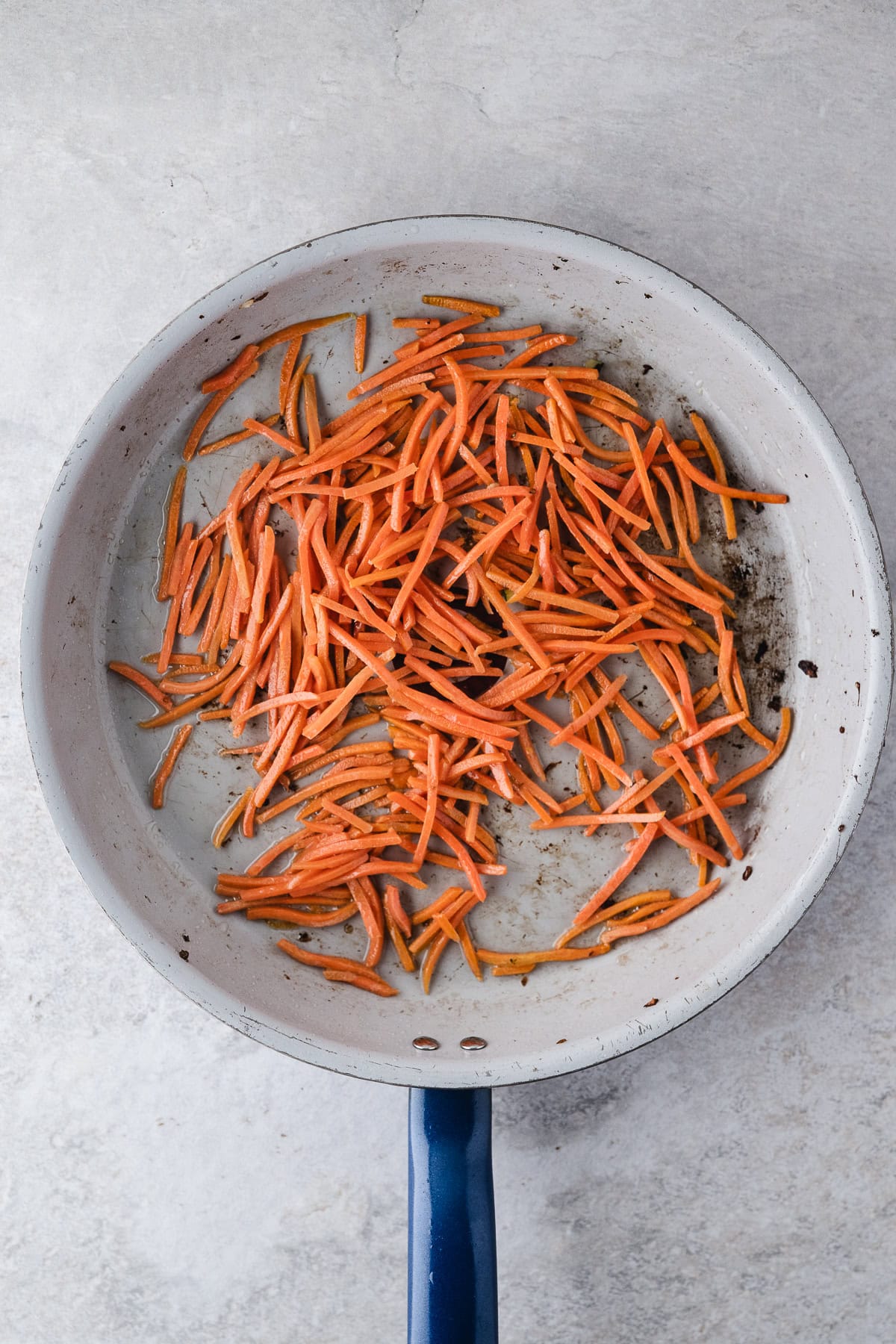 Shredded carrots in a pan with oil to soften them