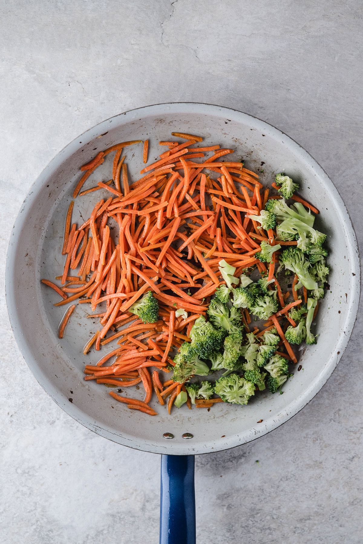 Saute shredded carrots and broccoli in oil in pan