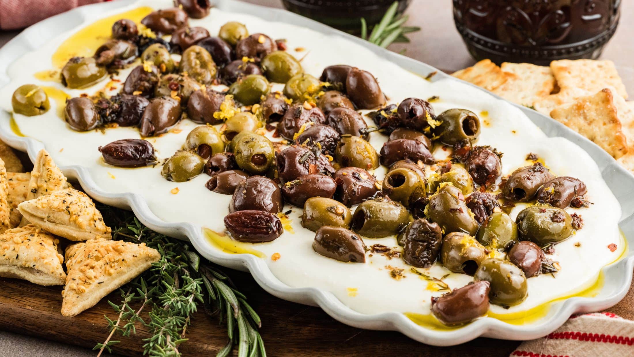 Whipped Feta Dip with olives on a white plate, crackers surrounding it