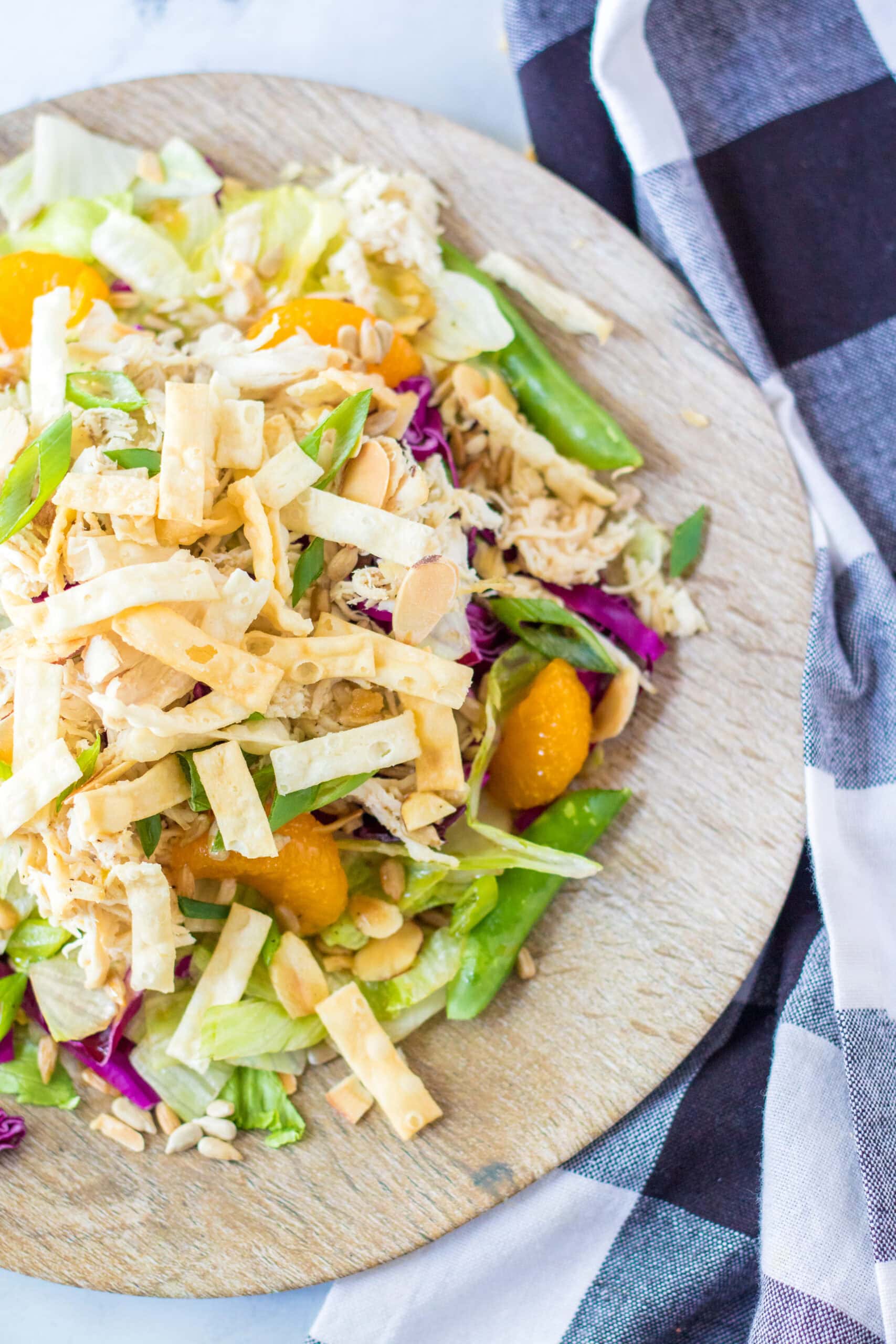 Chinese salad and dressing on a wooden plate