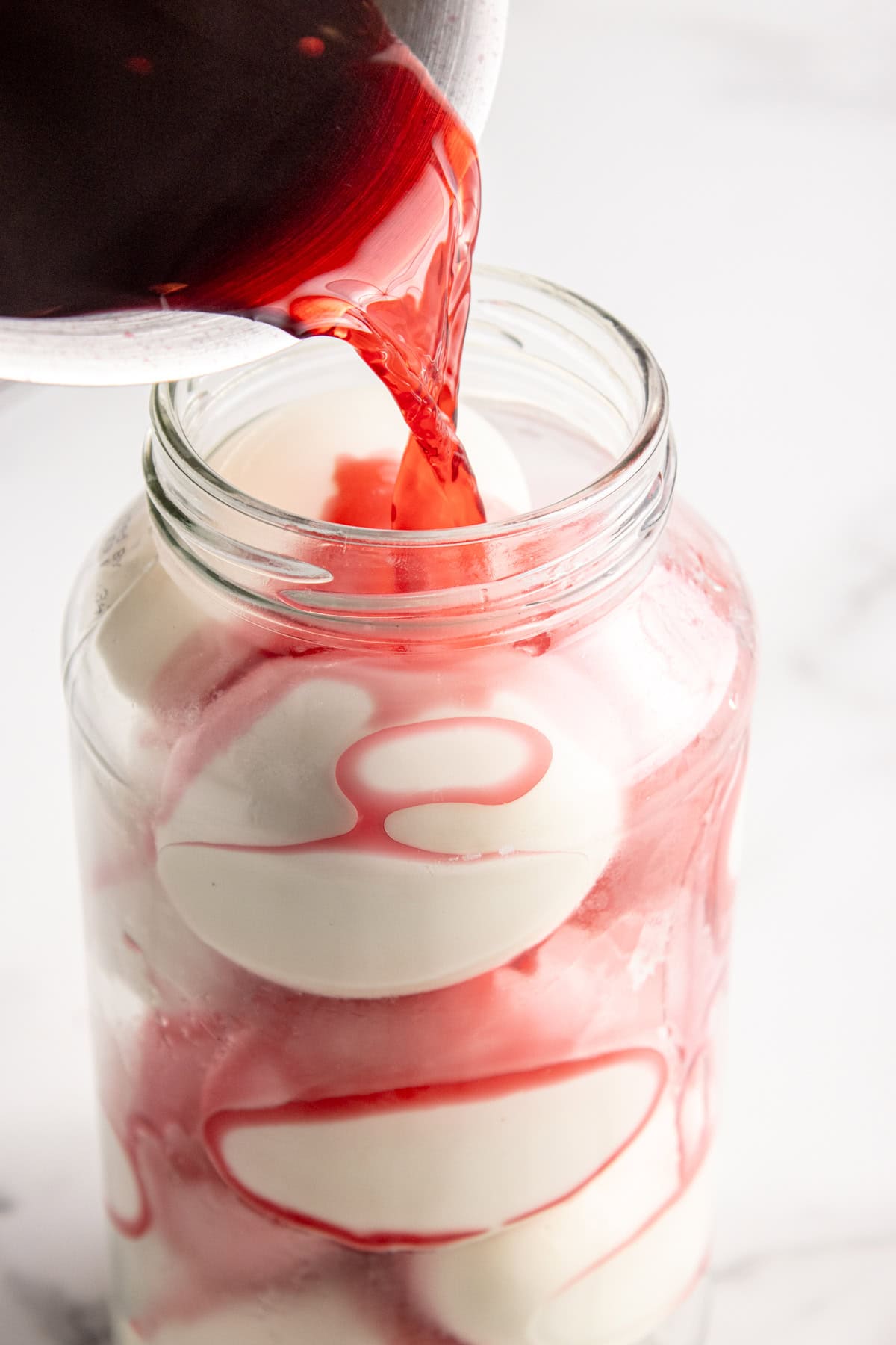 Pouring the warm brine into the sterilized jar with boiled eggs