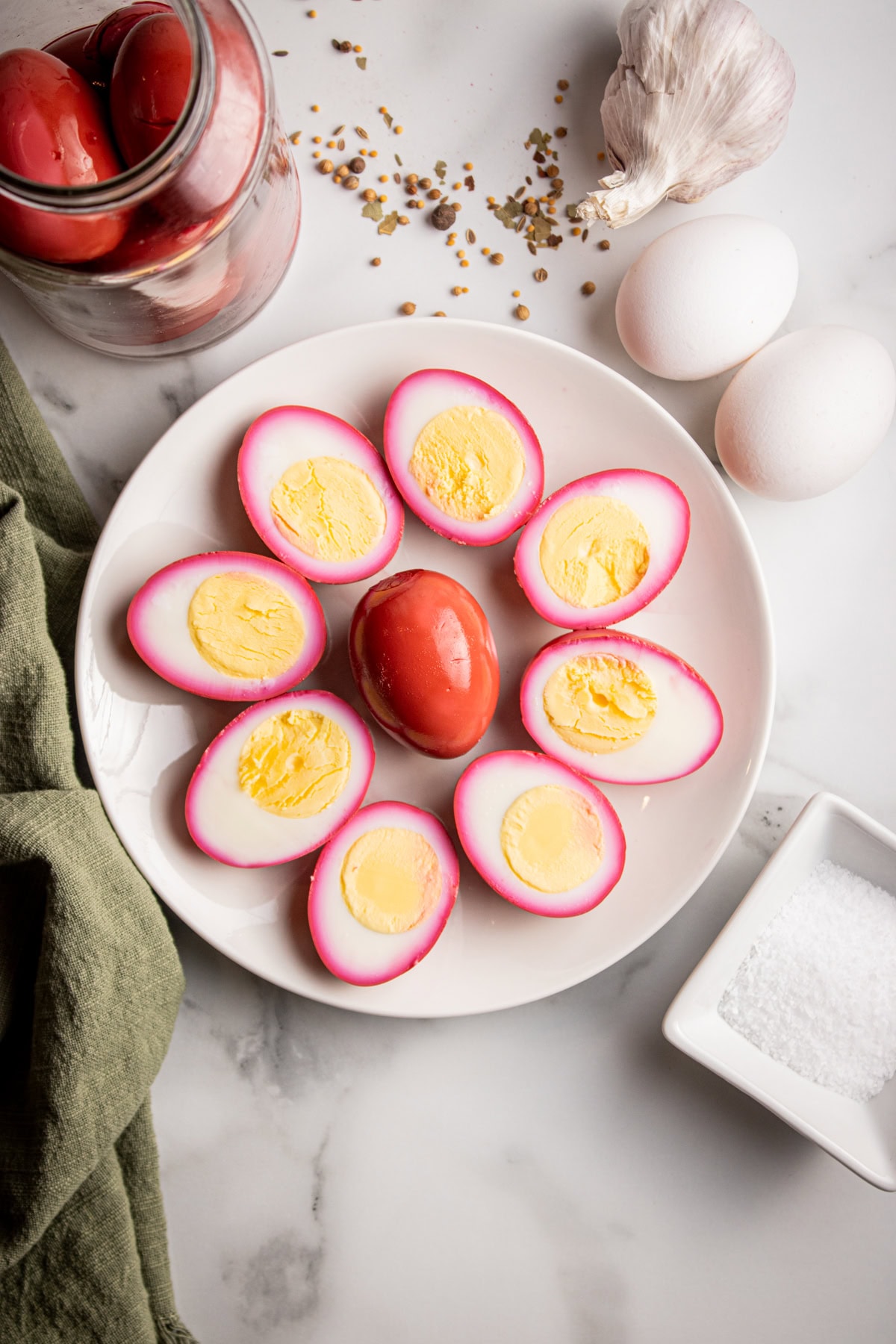 Pickled eggs on a plate, there's one egg full in the middle and cut eggs cut in half around the full egg