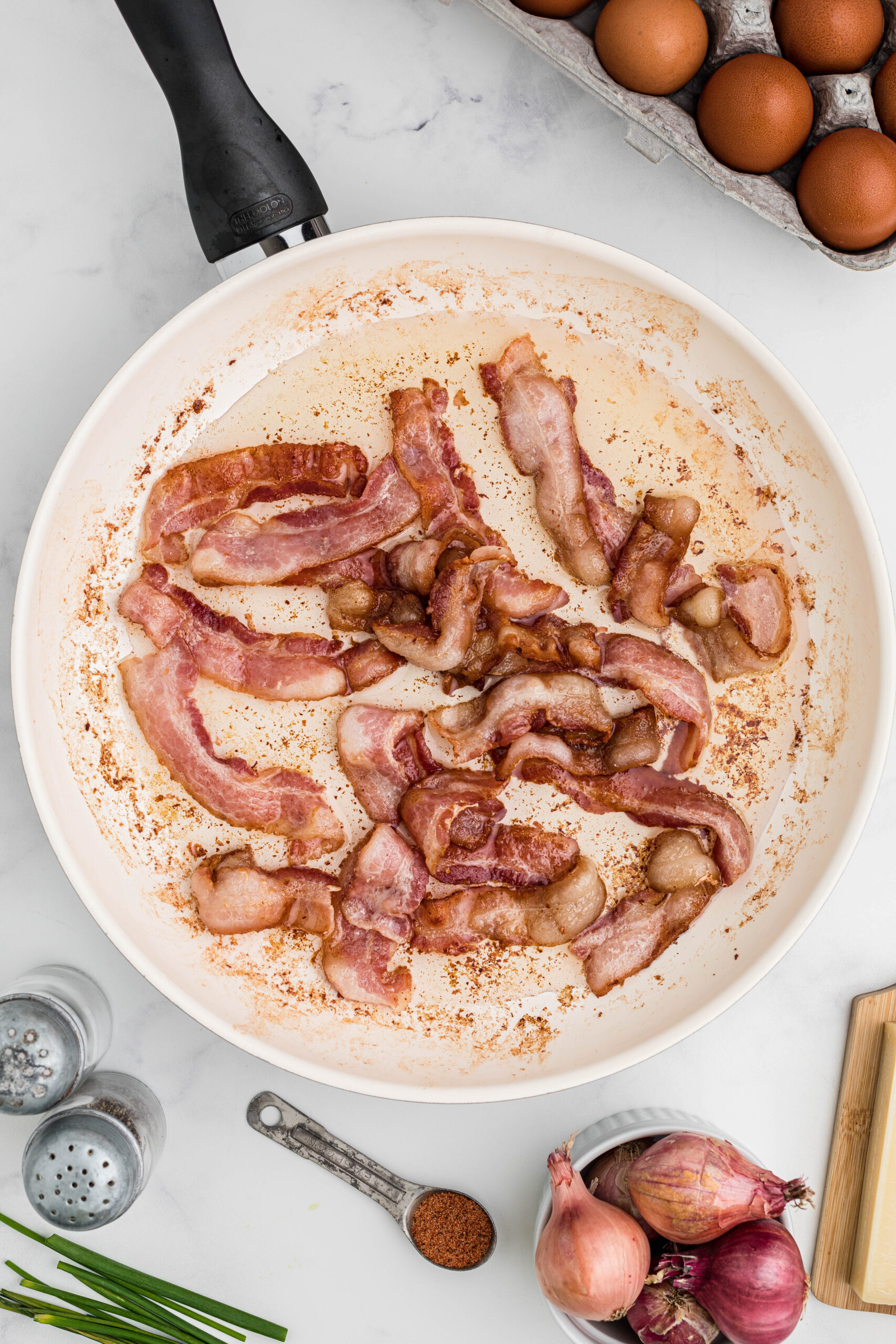 Cooking the bacon in a skillet, to add in the breakfast muffins